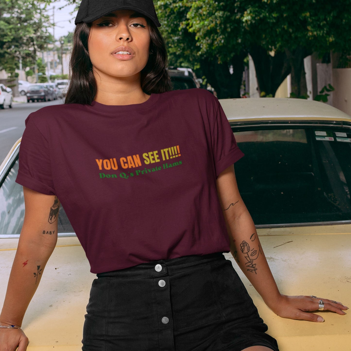 Lady on a car wearing a maroon t-shirt with multicolored 'you can see it!!!!' text.