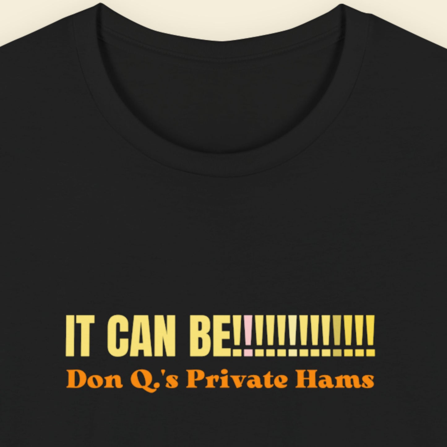 Black t-shirt with yellow and orange text on a beige background.