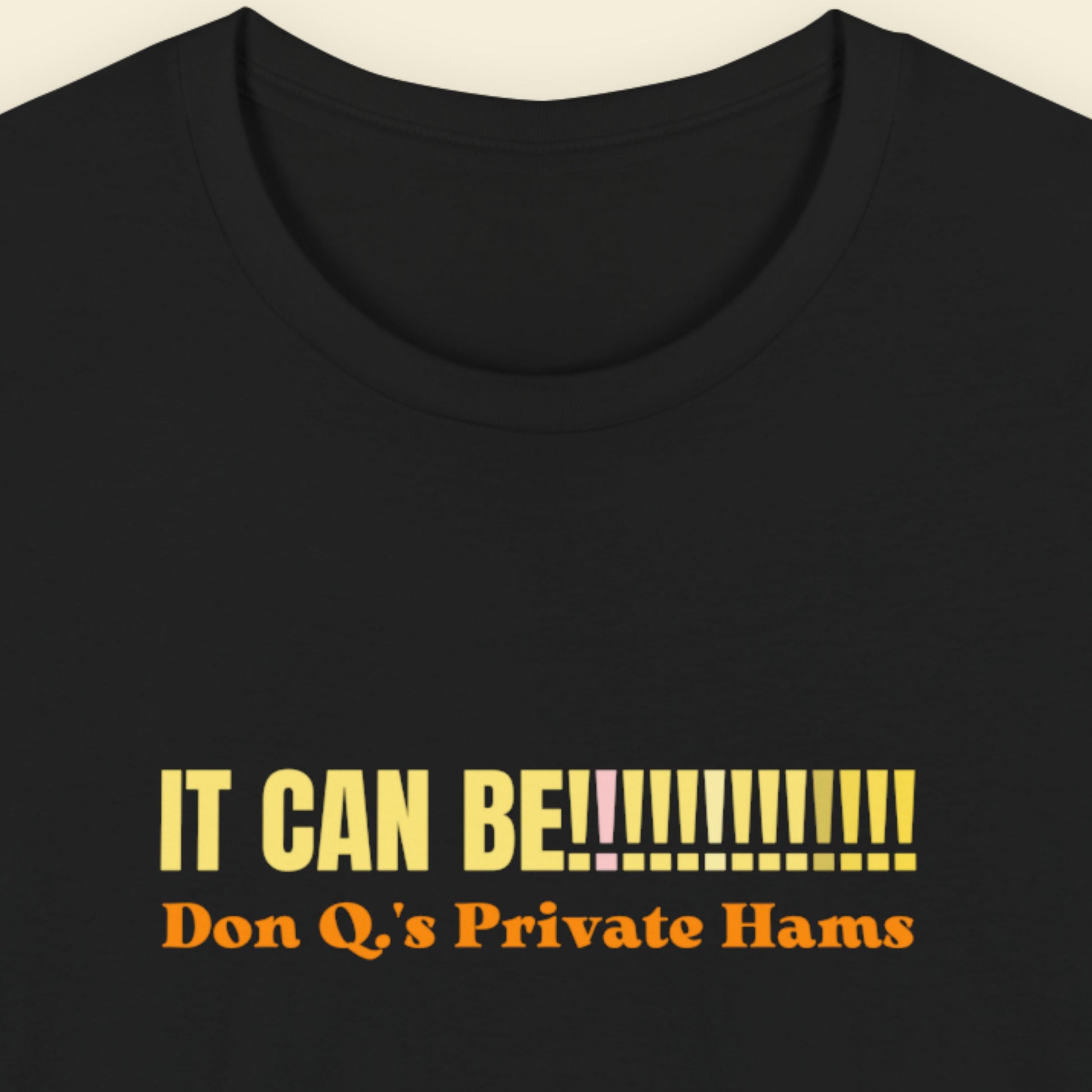 Black t-shirt with yellow and orange text on a beige background.