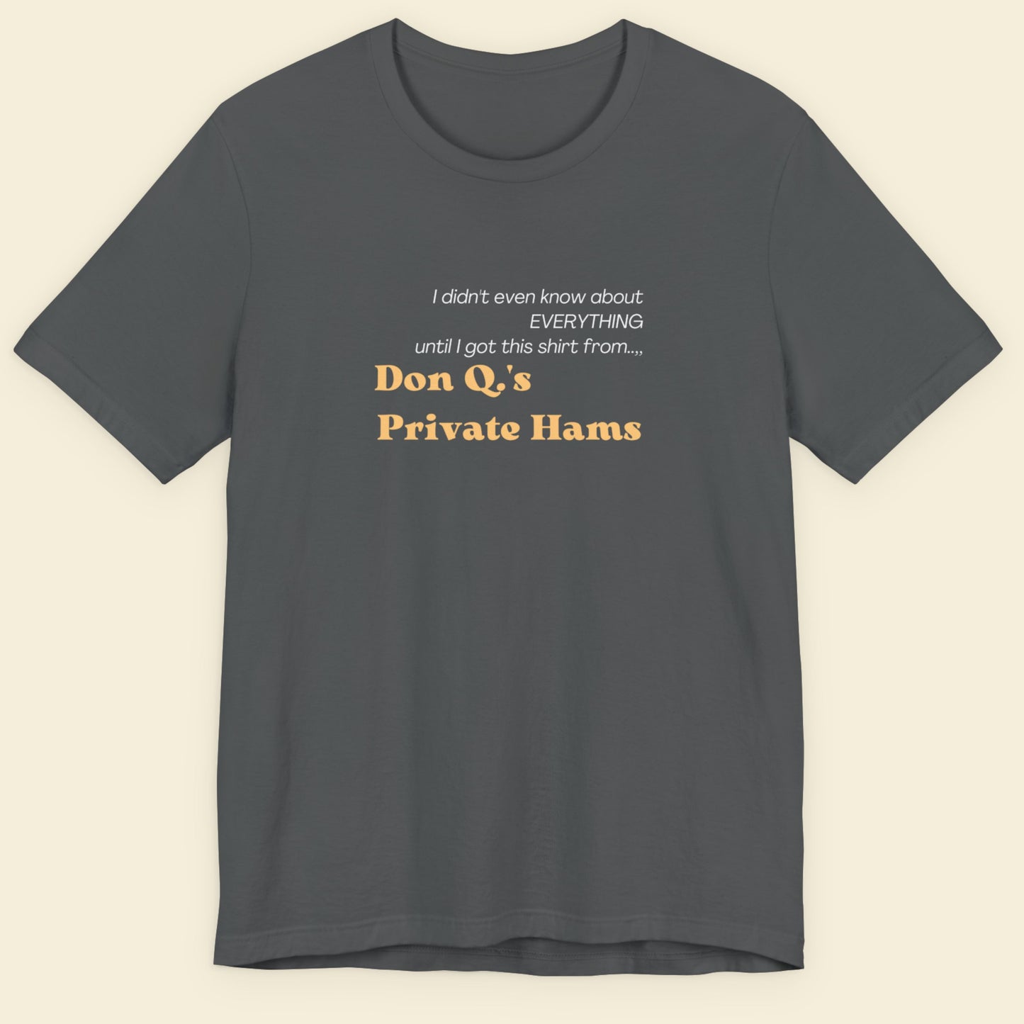 Gray t-shirt with humorous text design on a beige background.