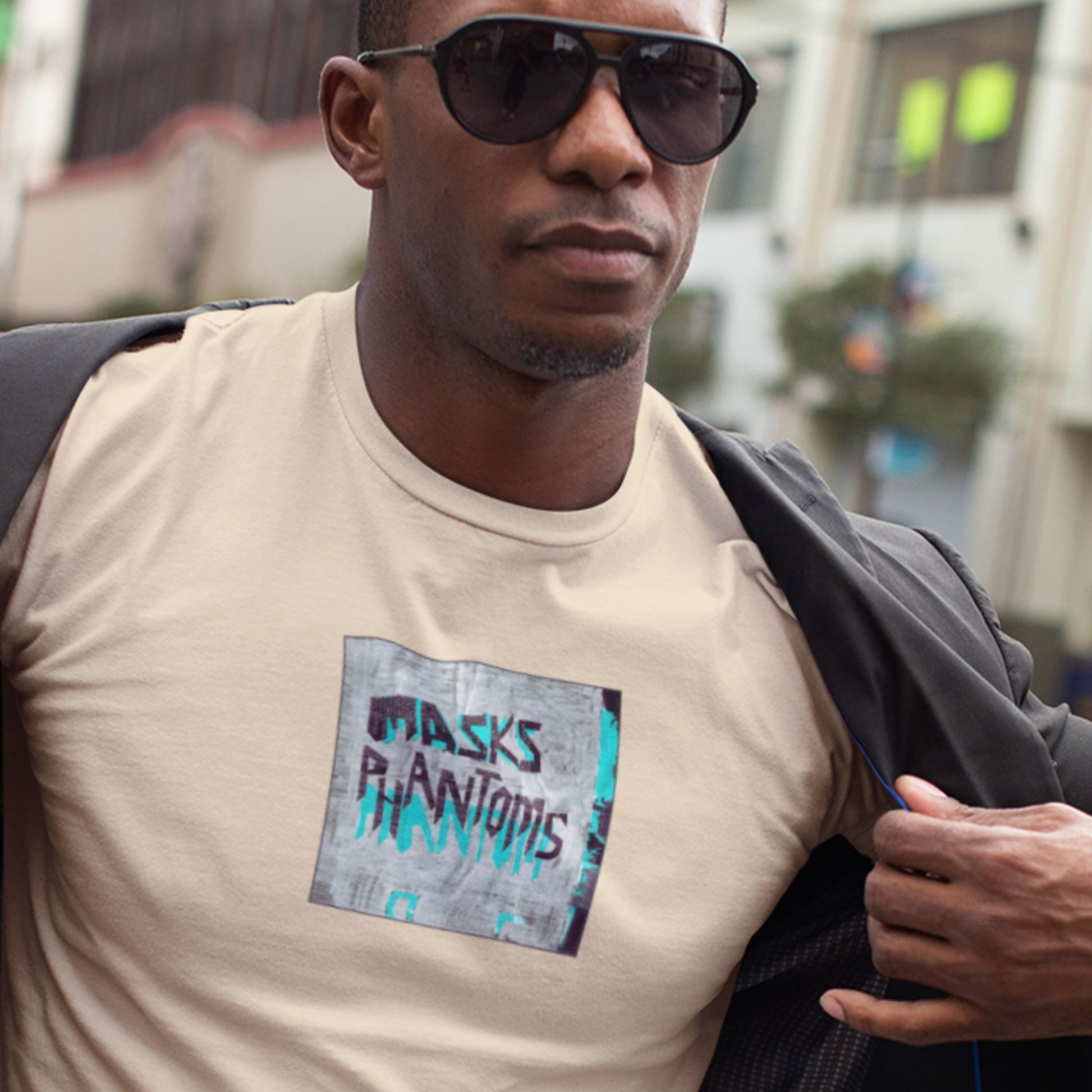 Man wearing sunglasses and a beige t-shirt with graphic design outdoors