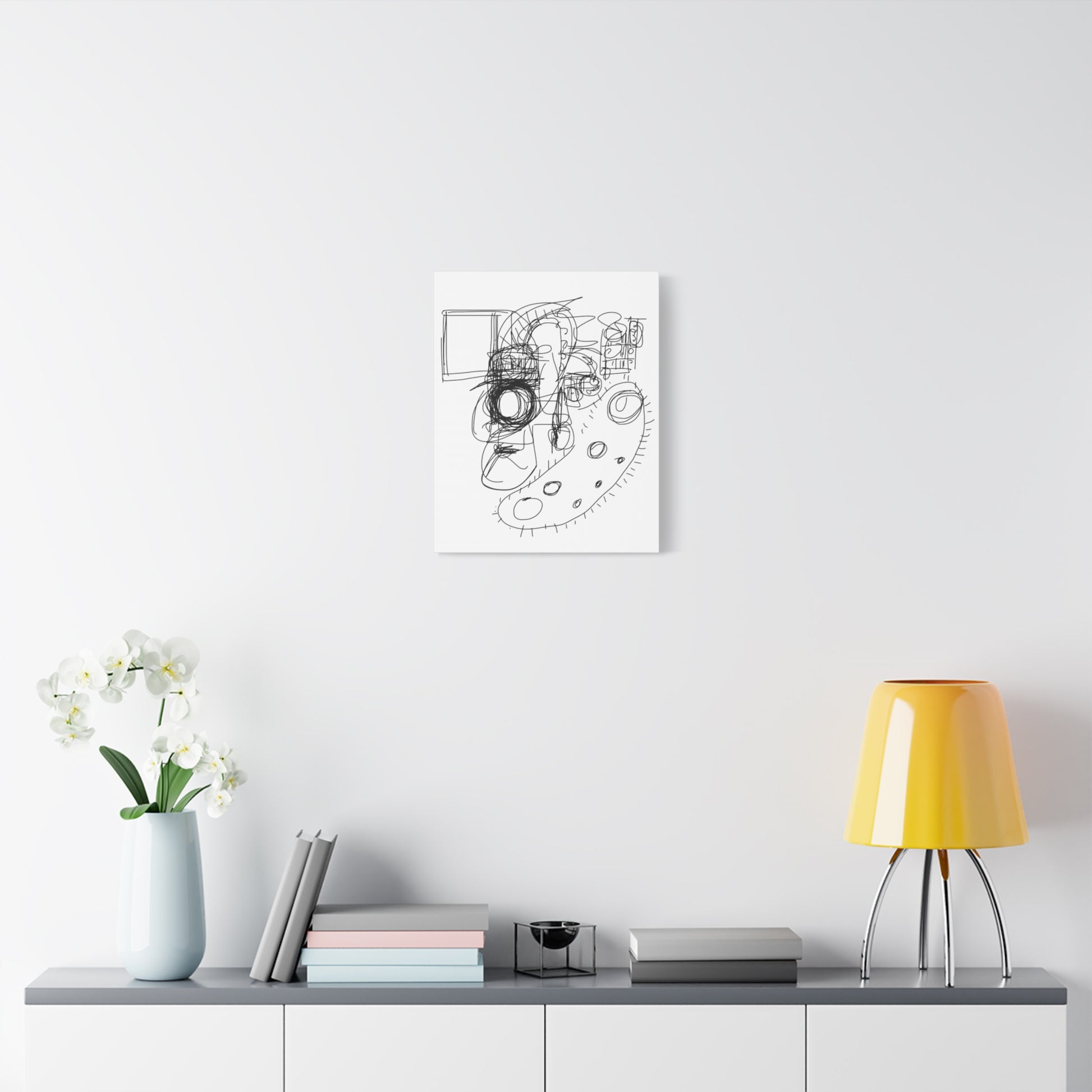 Framed black and white abstract art on a white wall above a shelf with decor items.