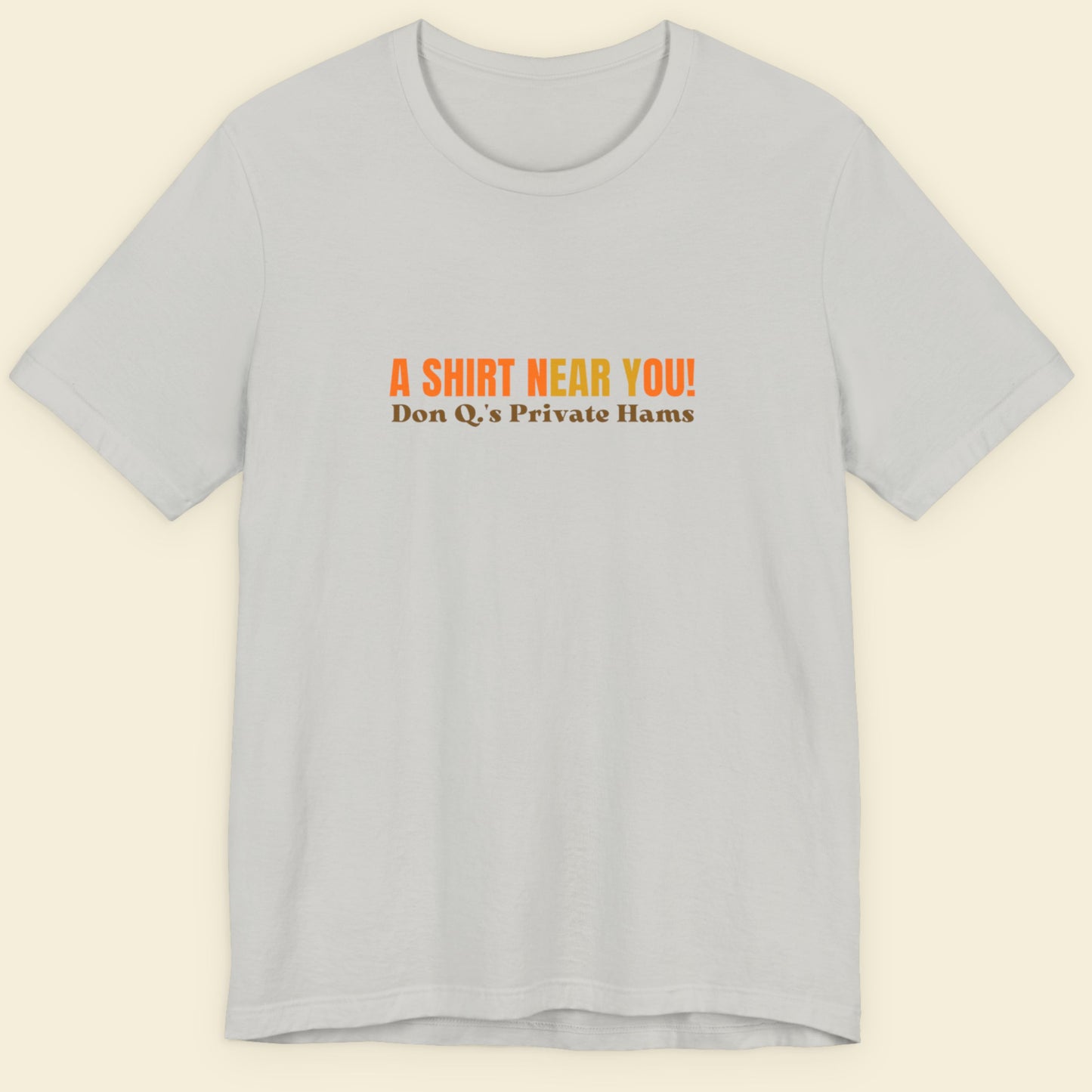 Silver t-shirt with multicolored 'A shirt near you!' text on a beige background.