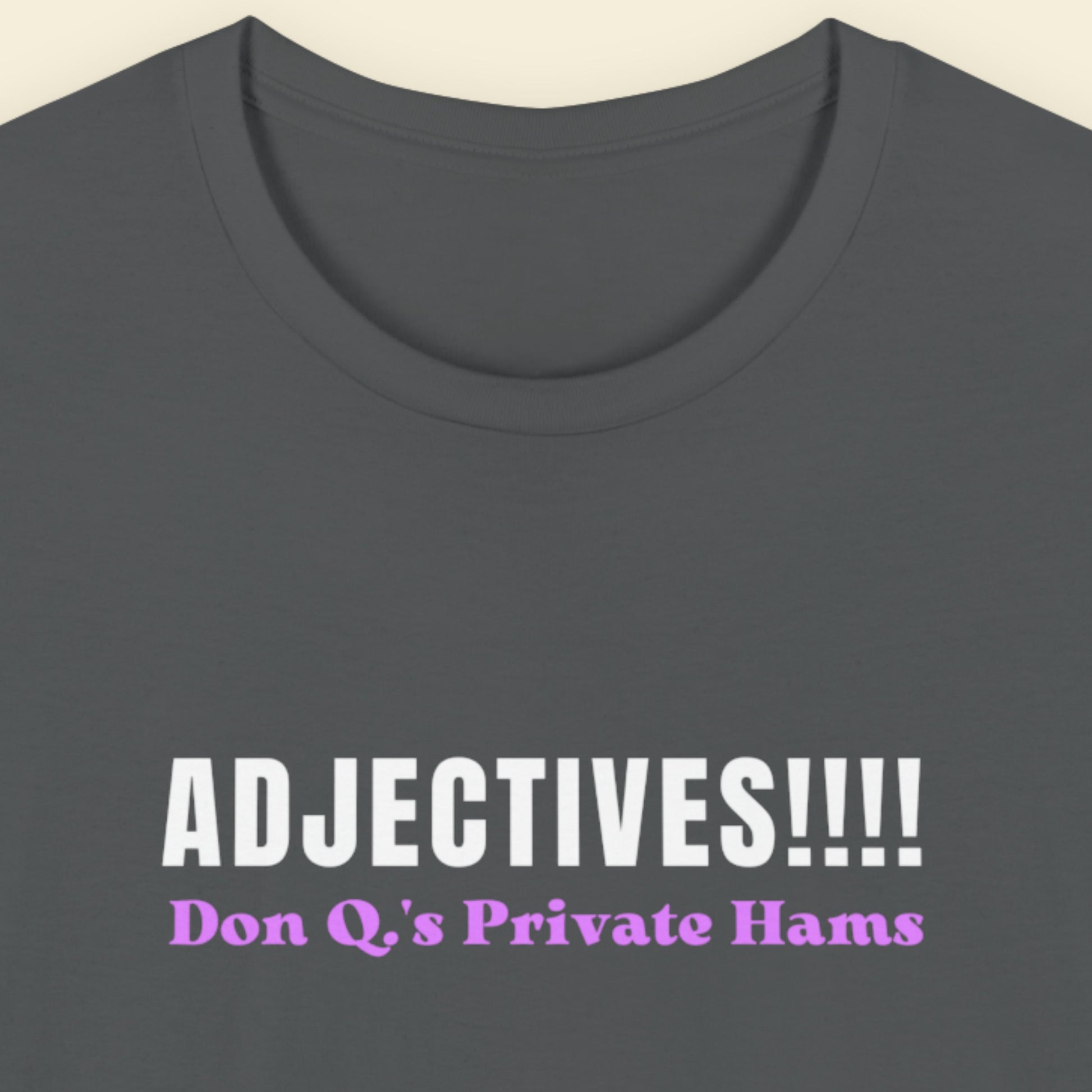 Grey t-shirt with humorous colorful text on a beige background.