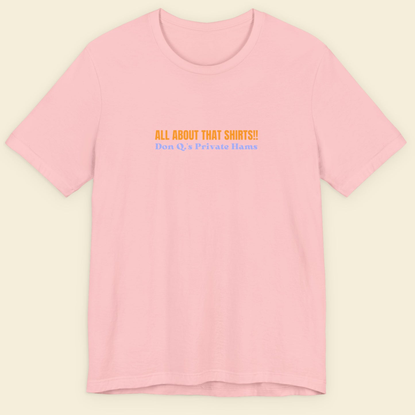 Pink t-shirt with multicolored 'all about that shirts!!' text on a beige background.