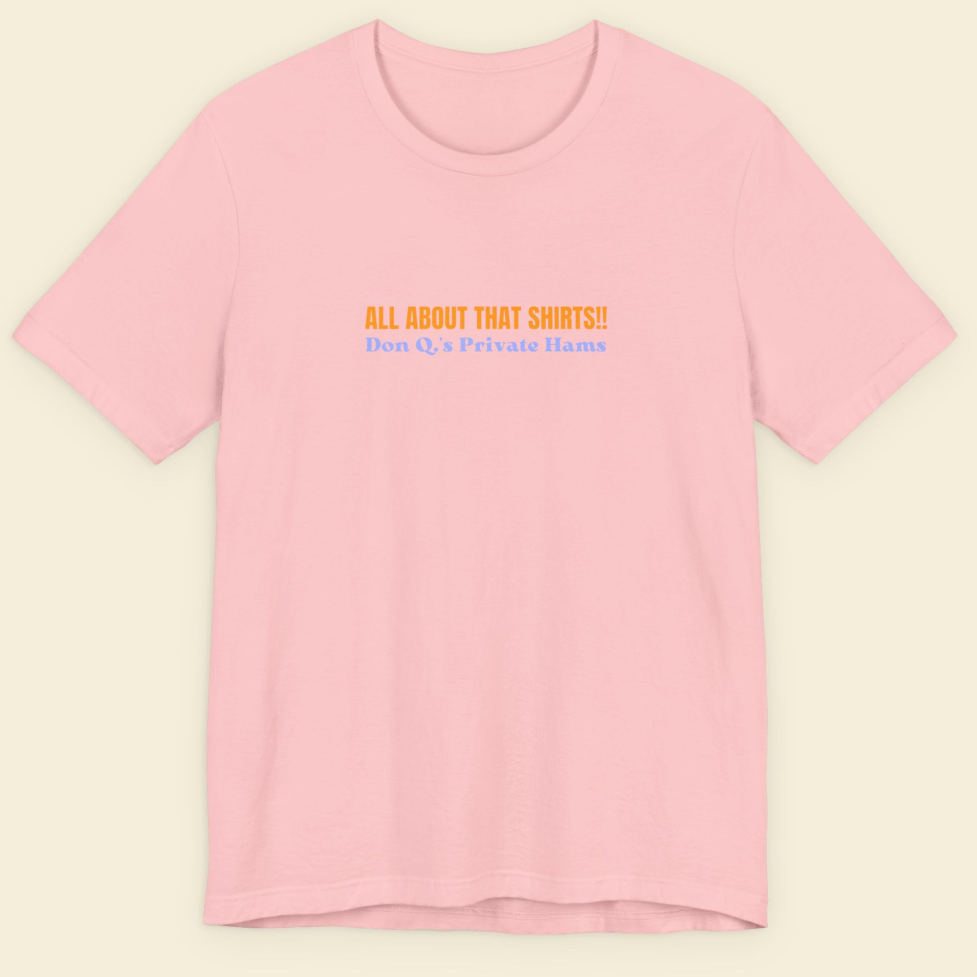Pink t-shirt with multicolored 'all about that shirts!!' text on a beige background.