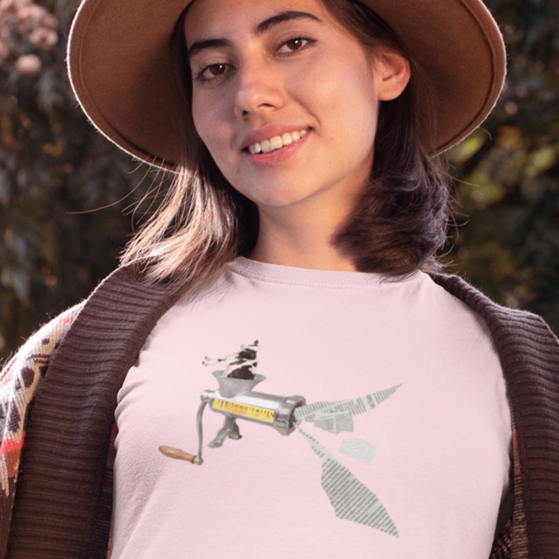 Smiling woman wearing a pink t-shirt with a fun, colorful cartoon illustration outside in the fall.