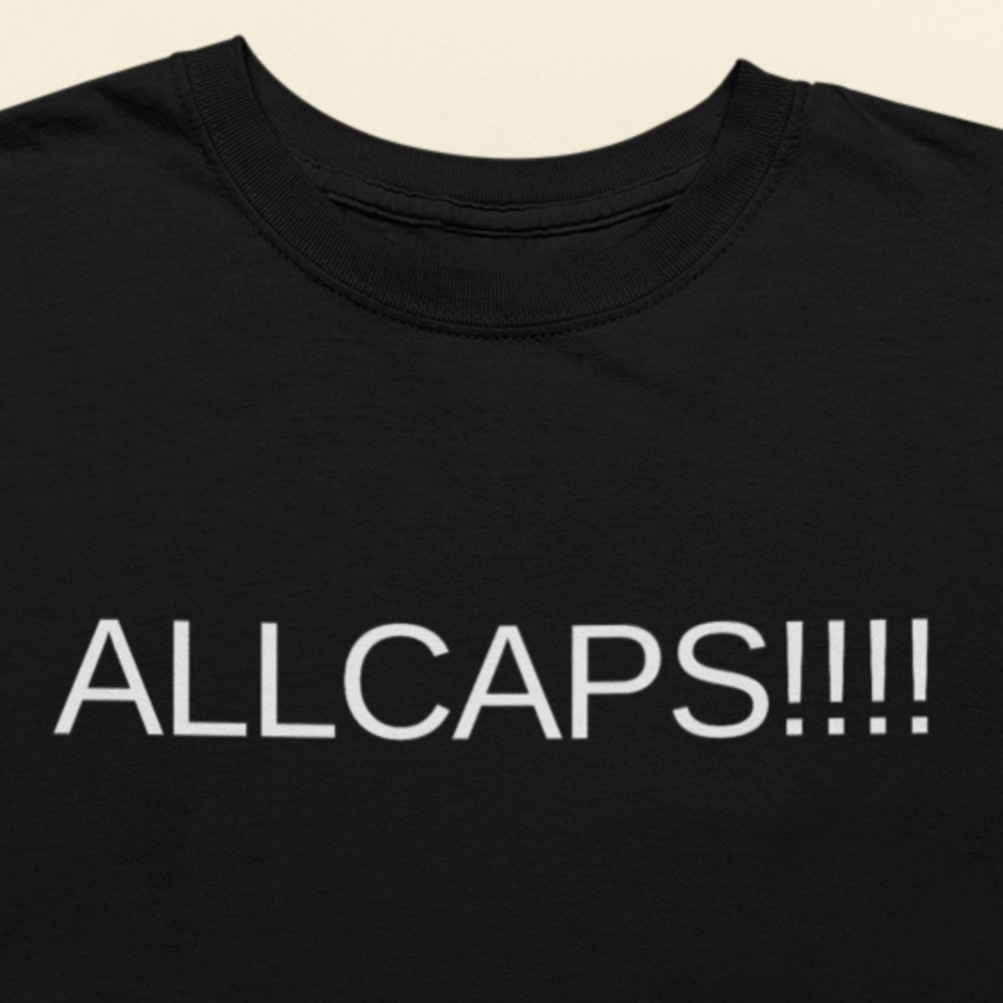 Black t-shirt with 'ALLCAPS!!!' text in white on a beige background