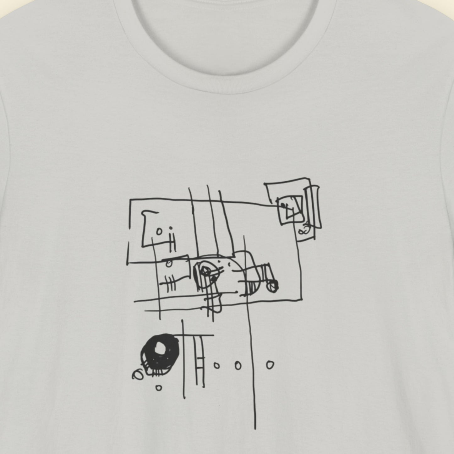 Grey t-shirt with an abstract line drawing on a beige background.