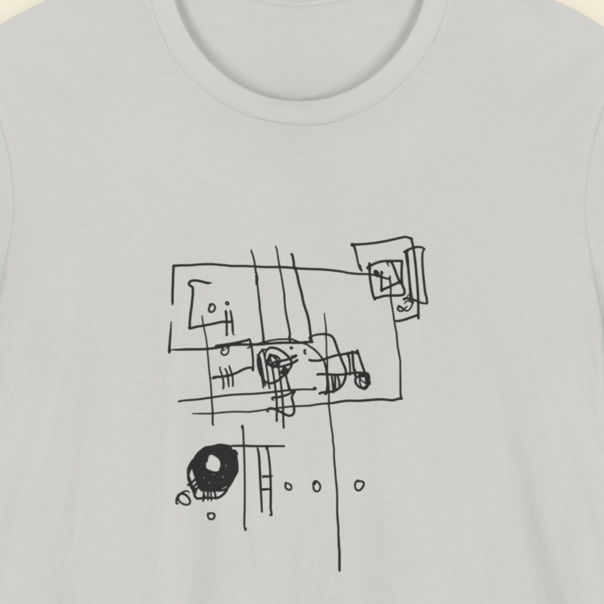 Grey t-shirt with an abstract line drawing on a beige background.