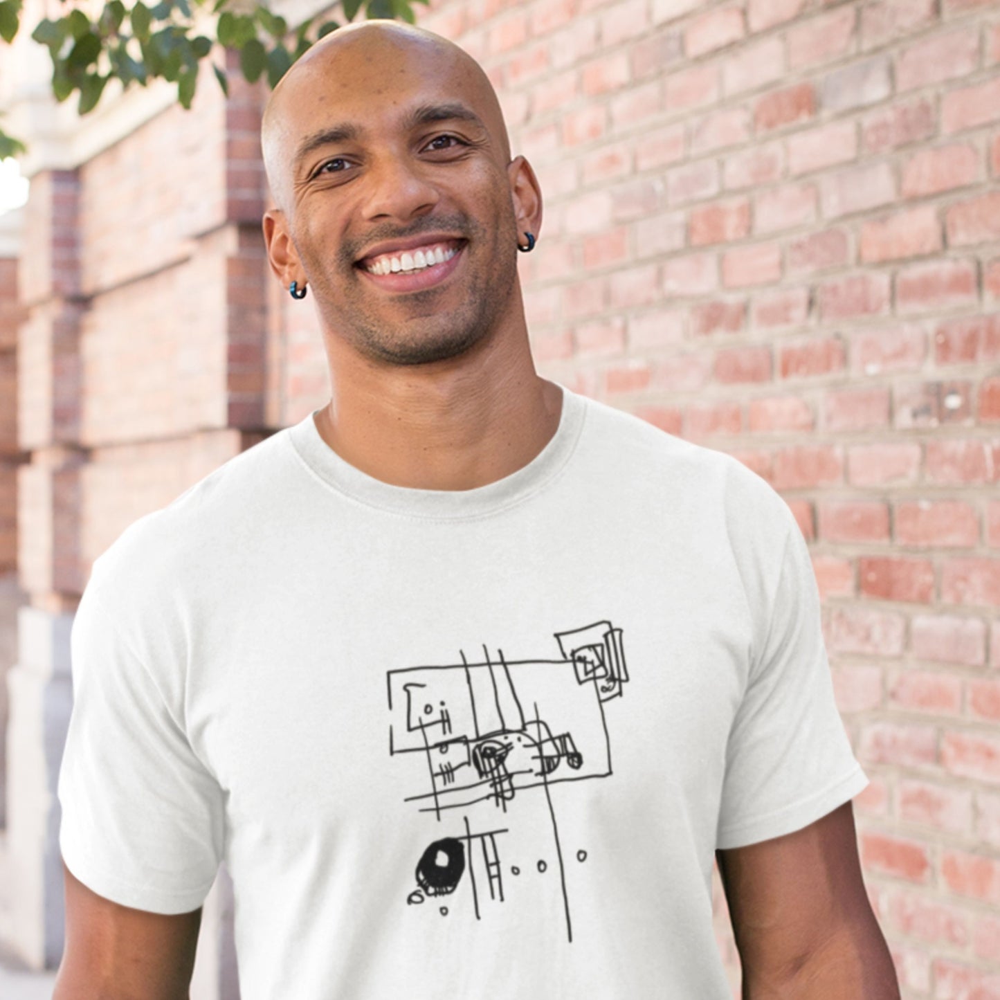 Smiling man wearing a white t-shirt with an abstract line drawing outside.