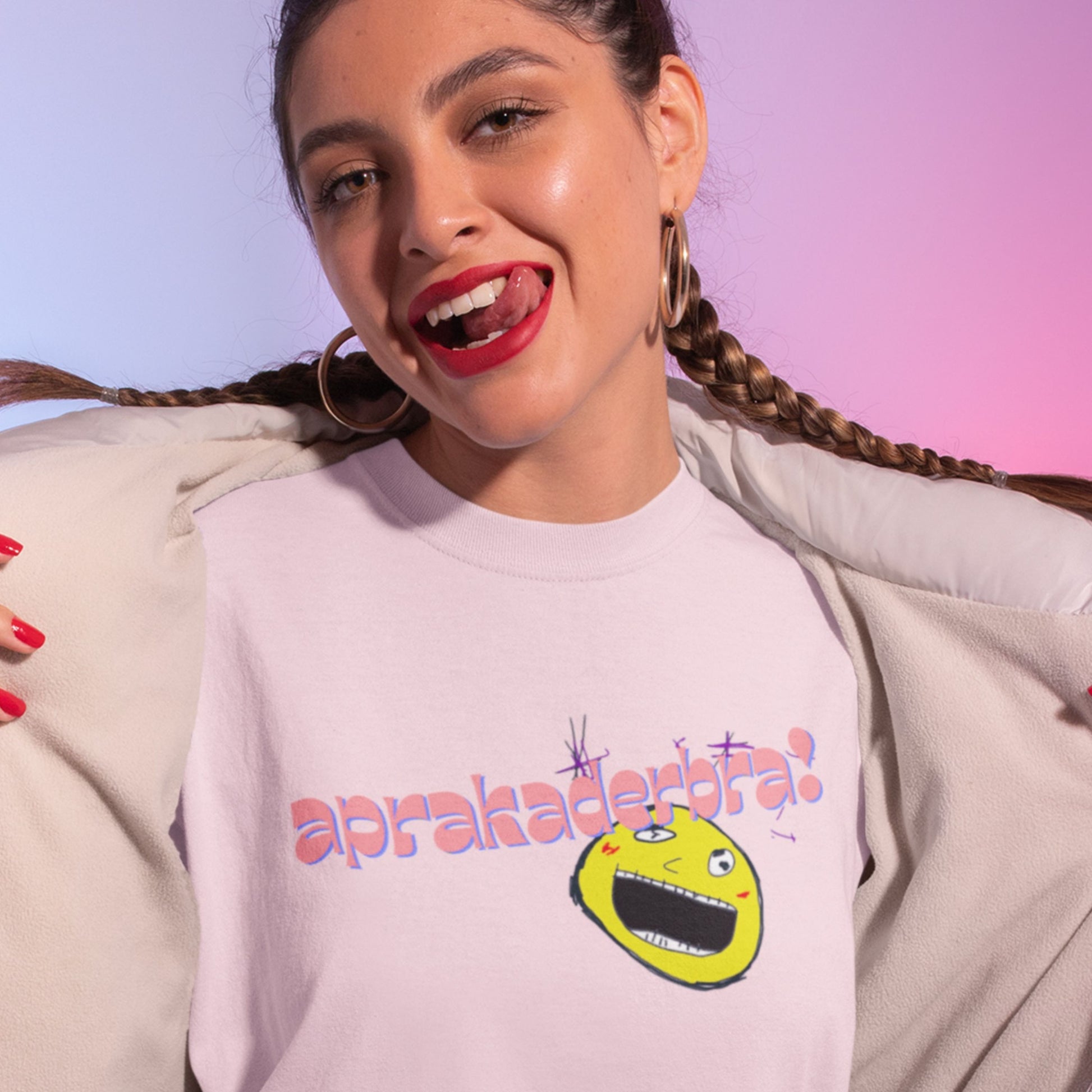 Woman wearing a light pink t-shirt with a colorful graphic design on a gradient background.
