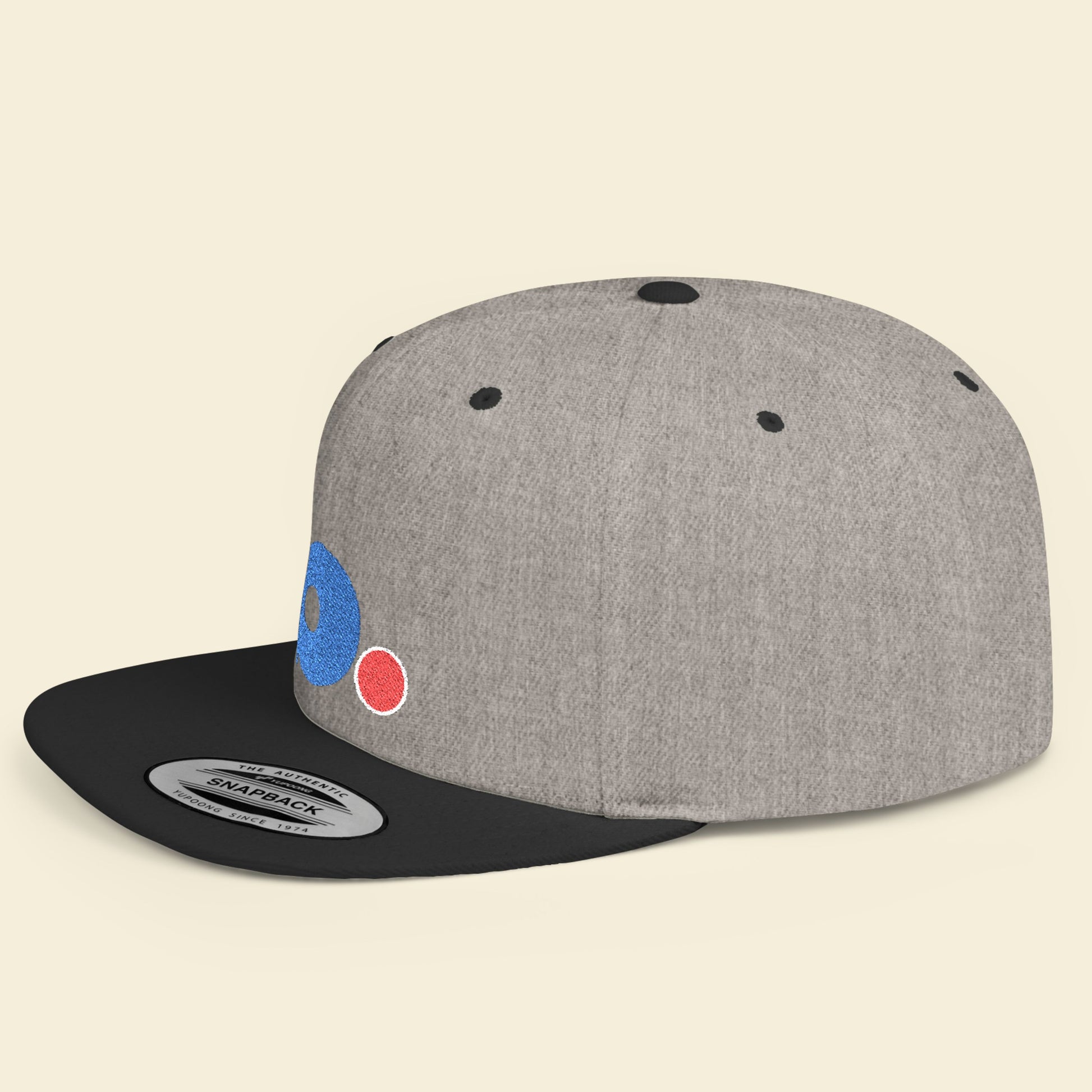 Gray and black cap with colorful b. logo on a beige background.