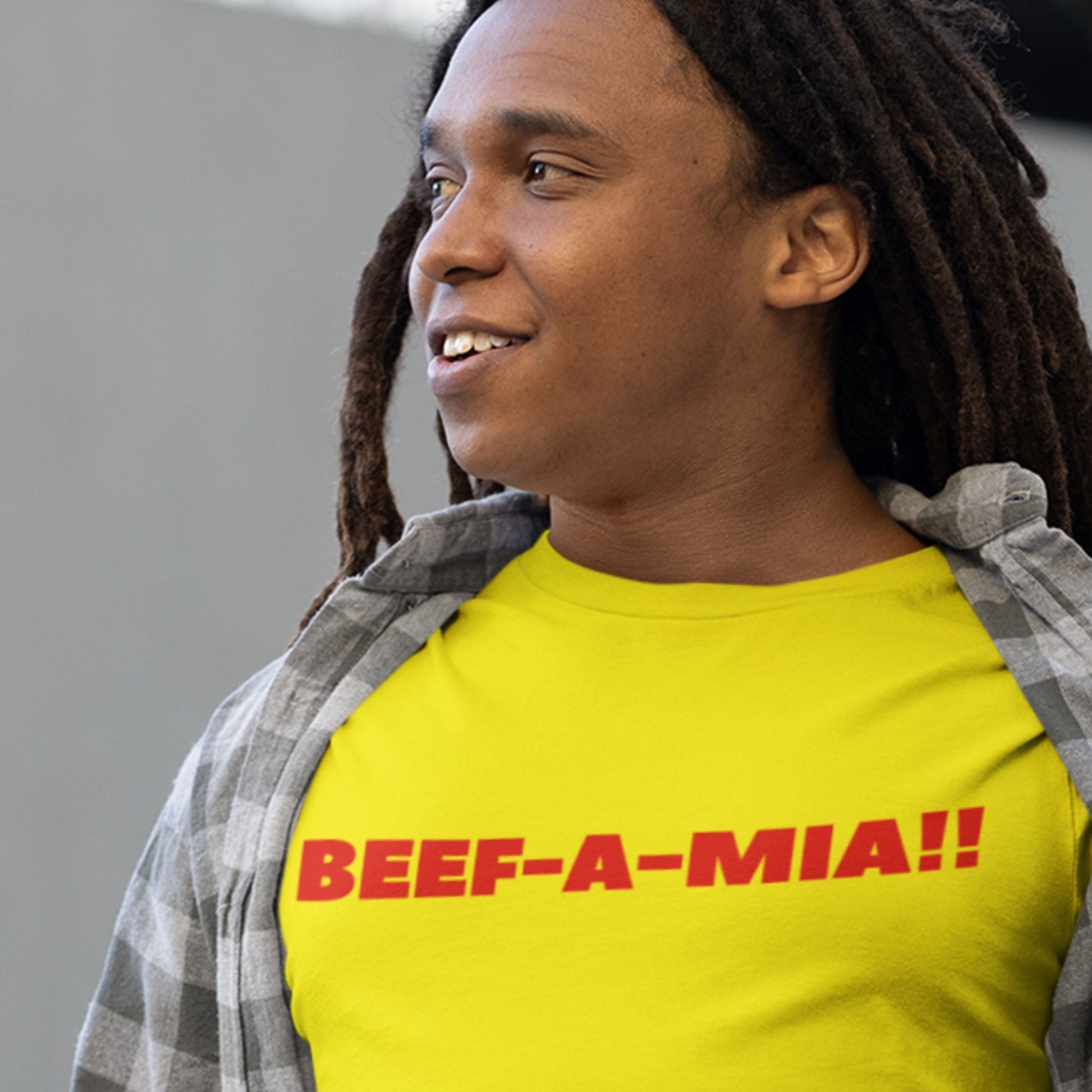Man wearing a yellow t-shirt with humorous colorful text on a beige background.