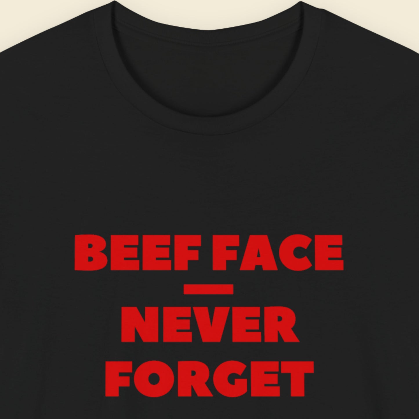 Black tee with humorous beef face text on a beige background.