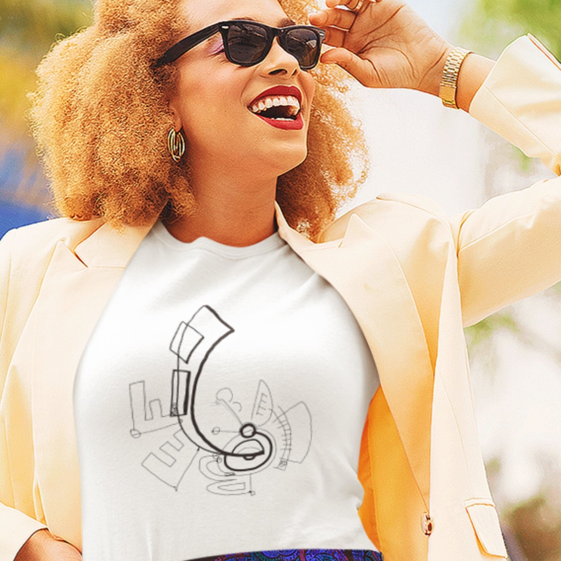 Woman wearing sunglasses and a white t-shirt with a graphic design, outdoors.