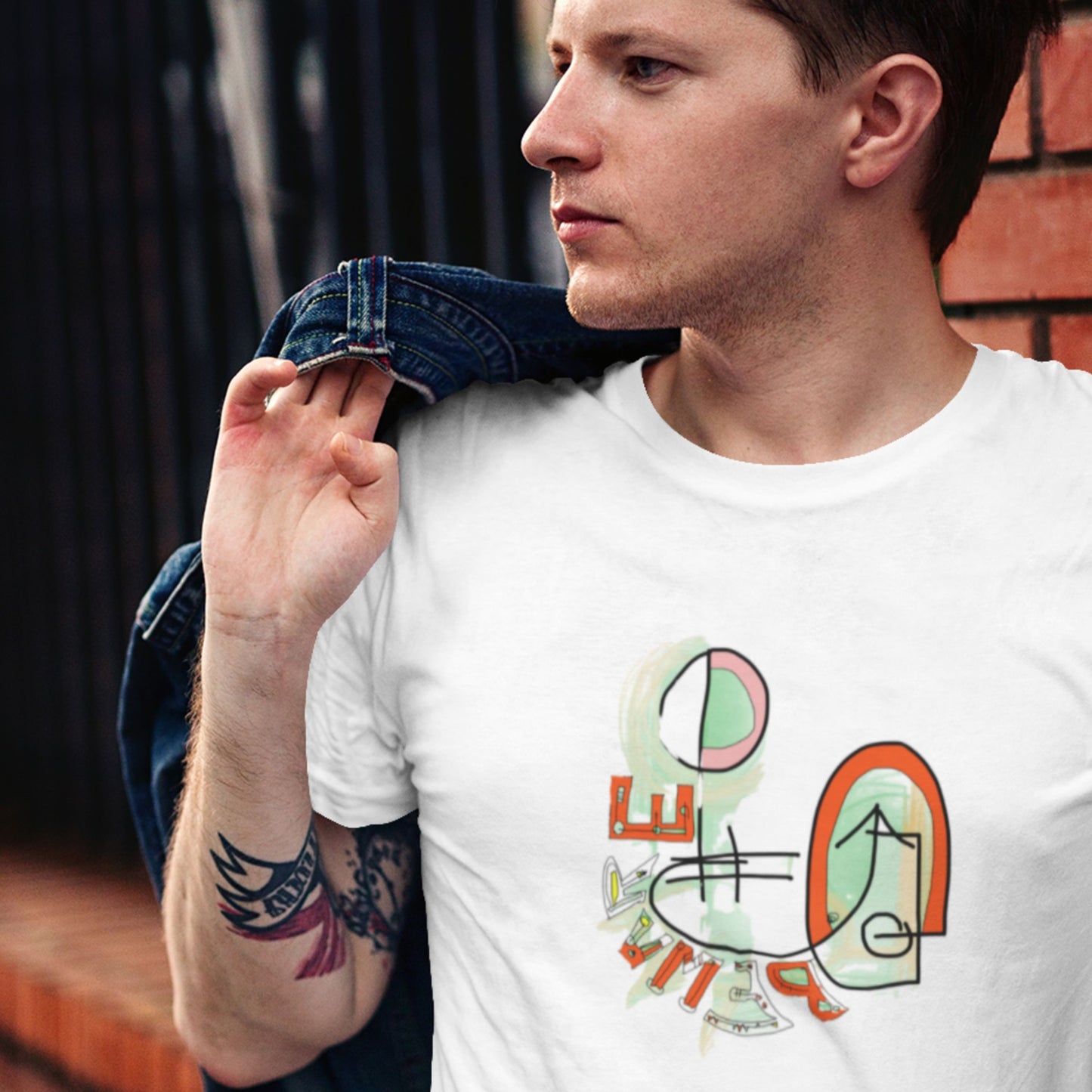Man wearing a white t-shirt with colorful abstract design, standing against a blurred background.