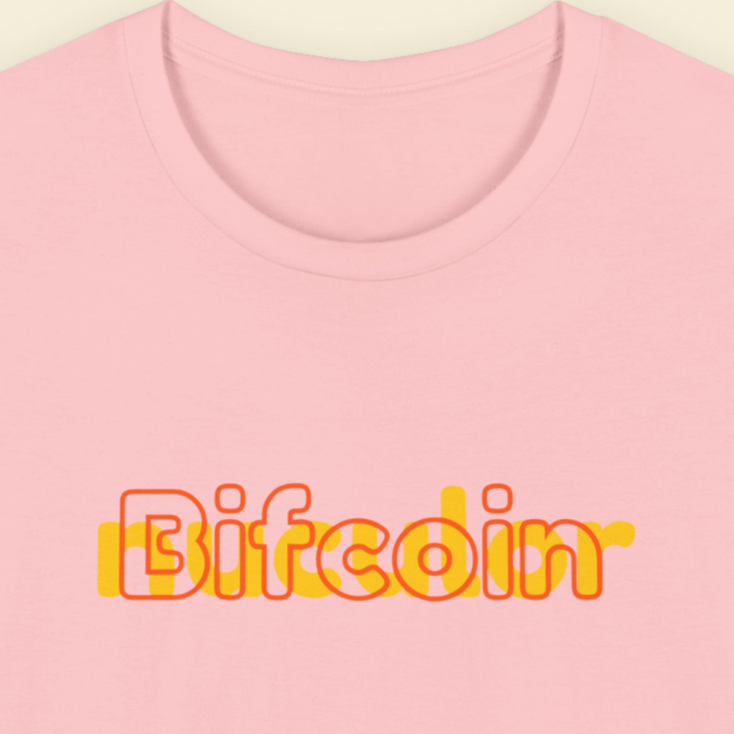 Pink t-shirt with humorous colorful text on a beige background.
