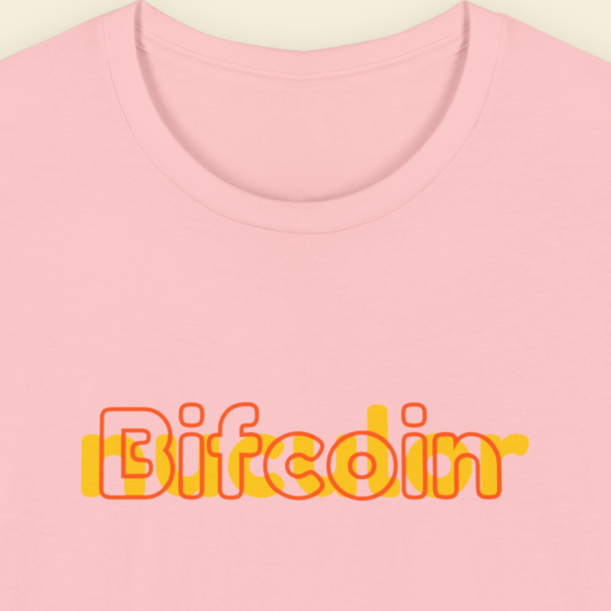 Pink t-shirt with humorous colorful text on a beige background.