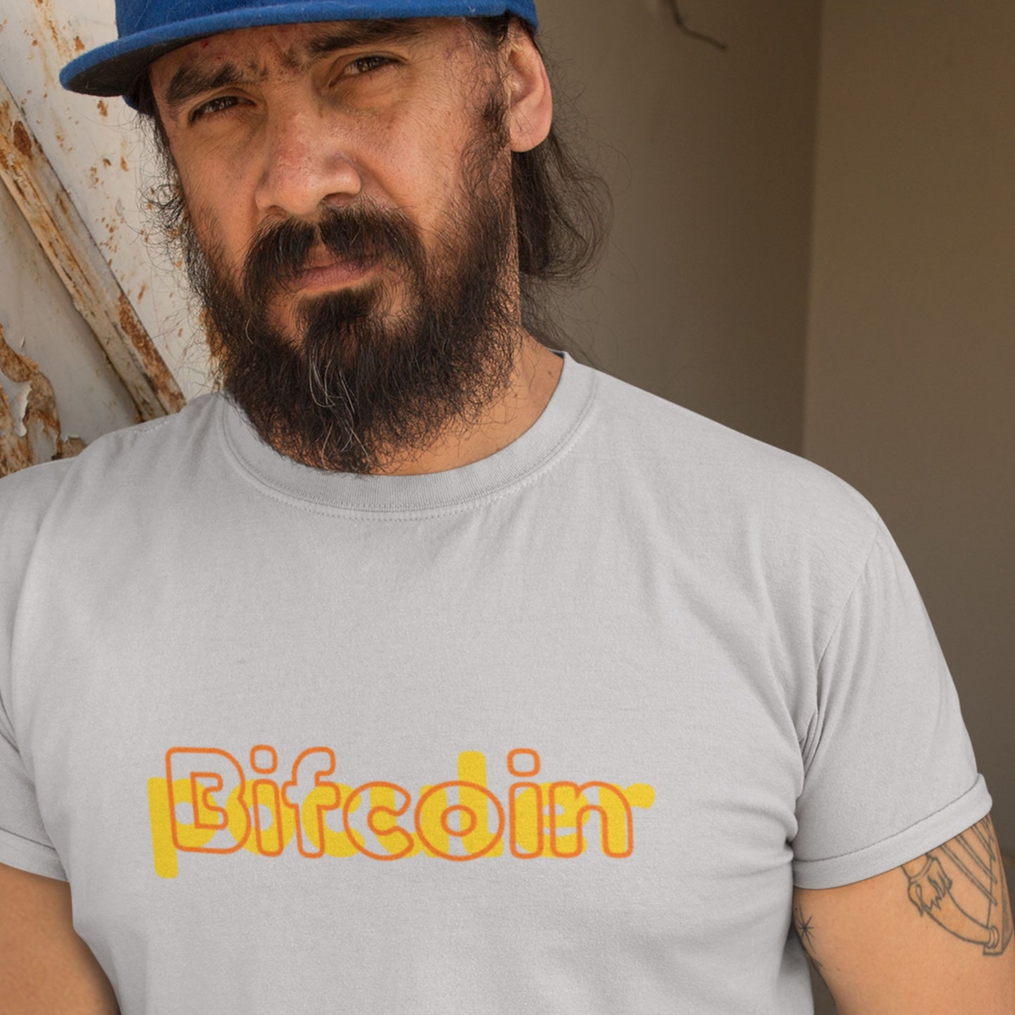 Man wearing a gray t-shirt with 'Bitcoin' printed on it, standing against a neutral background.