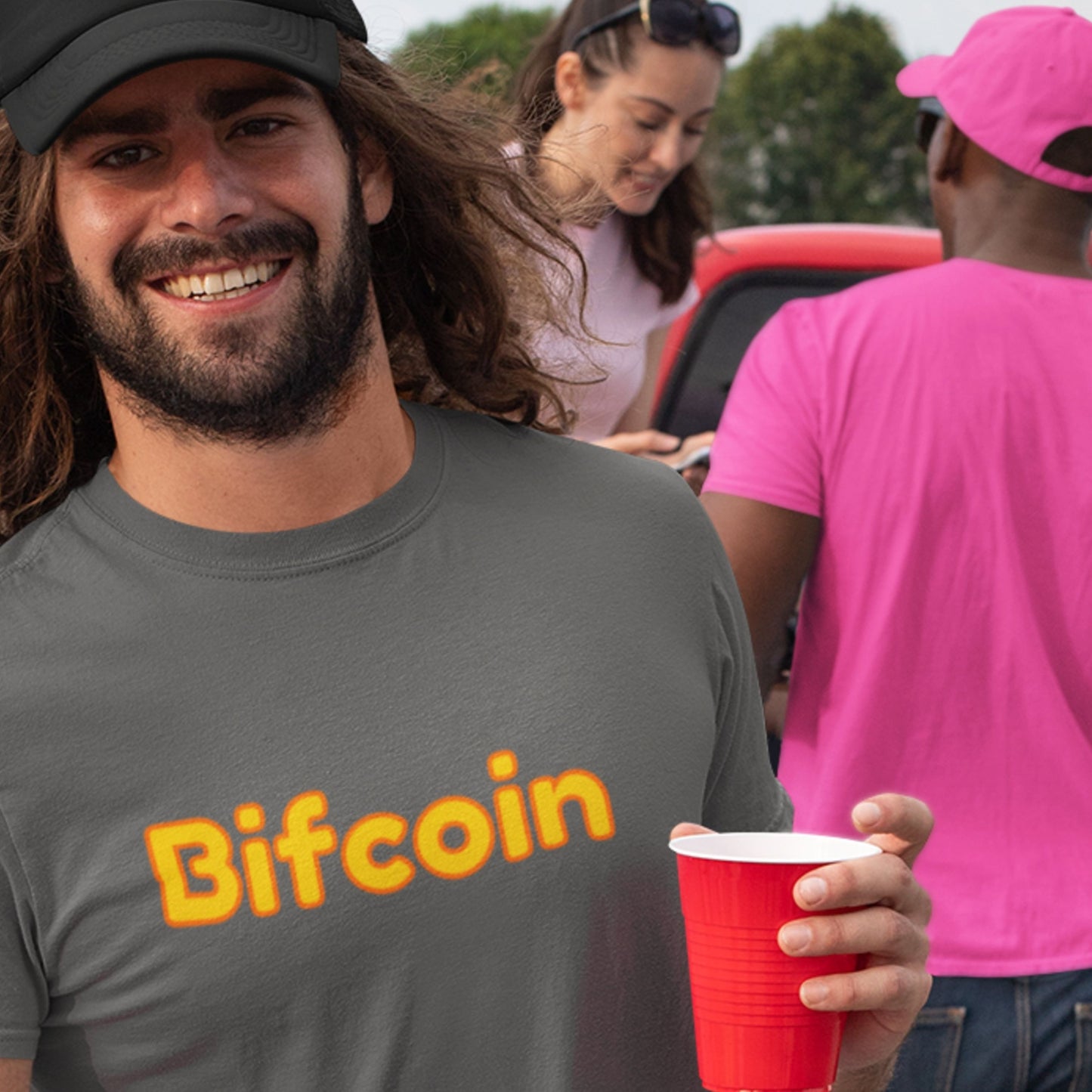 Party man wearing a 'Bifcoin' shirt holding a red cup with people in the background.