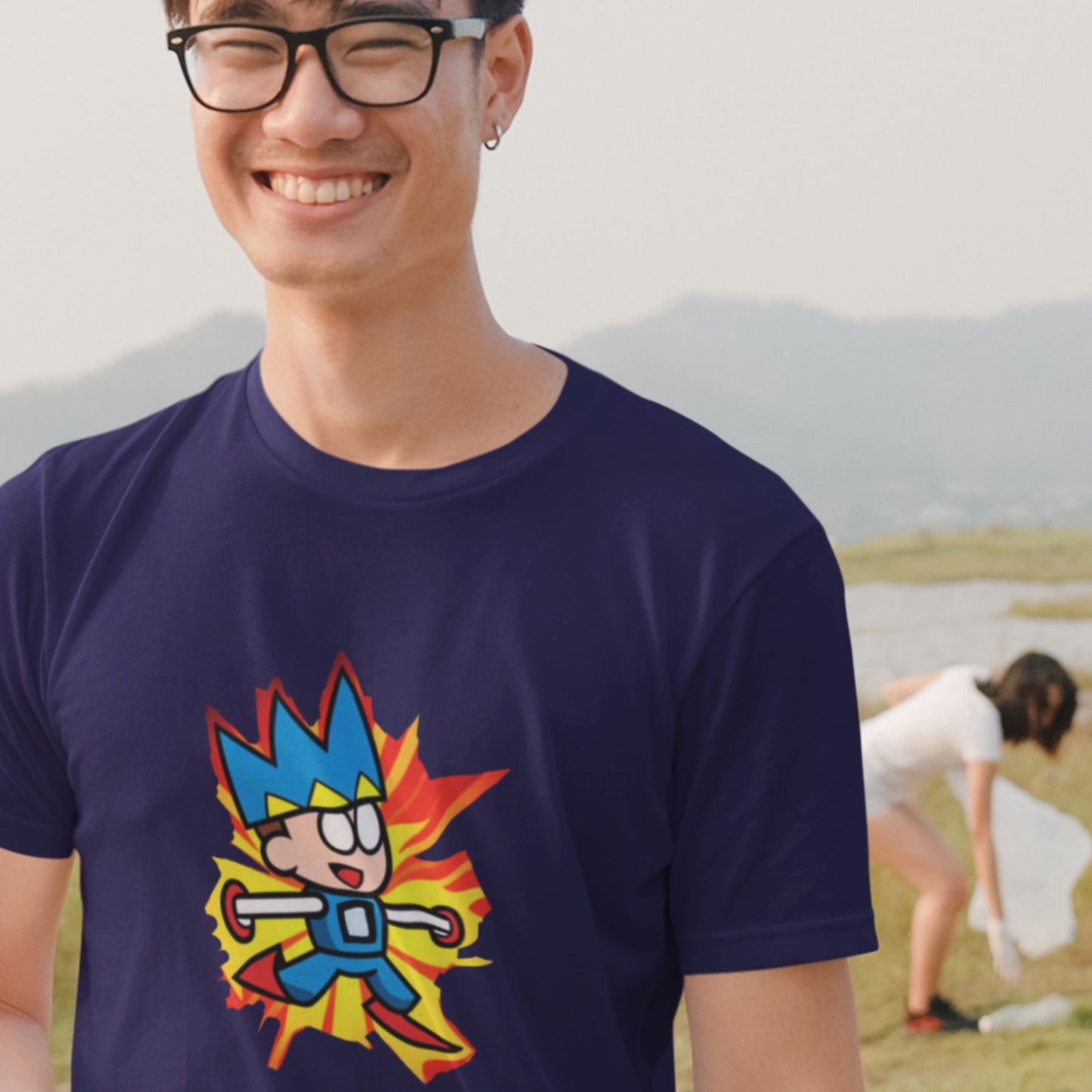 Laughing man wearing a navy blue t-shirt with a fun, colorful cartoon illustration on a beach.