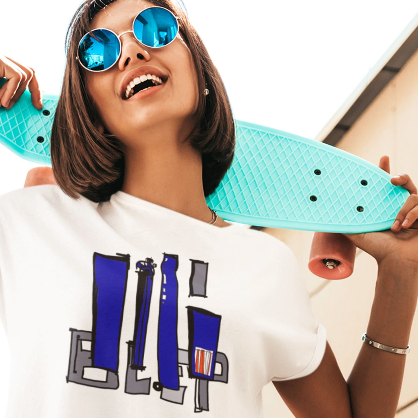 Woman holding a turquoise skateboard with a white t-shirt featuring blue and gray graphics.