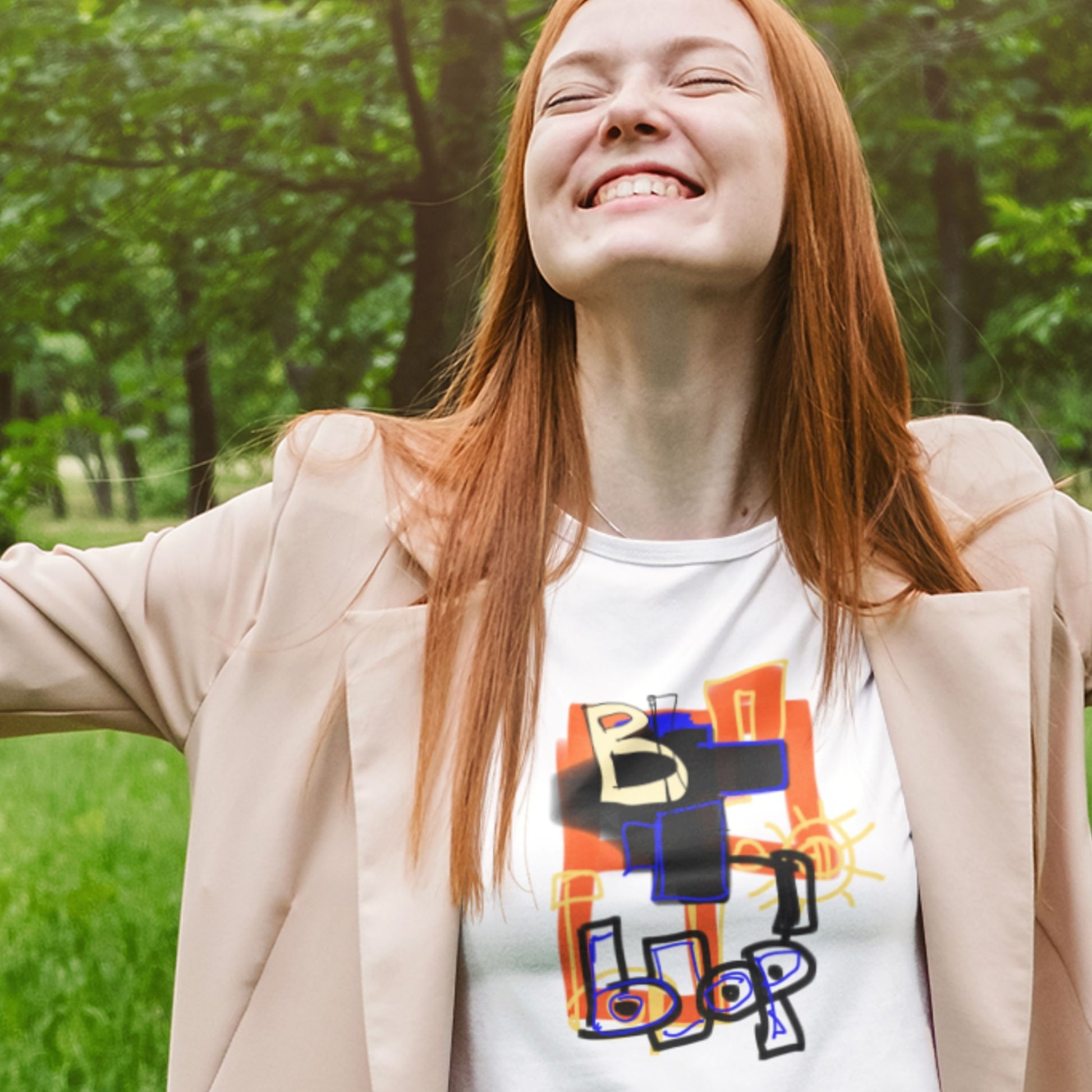 Happy woman wearing a white t-shirt with a colorful abstract drawing outside.