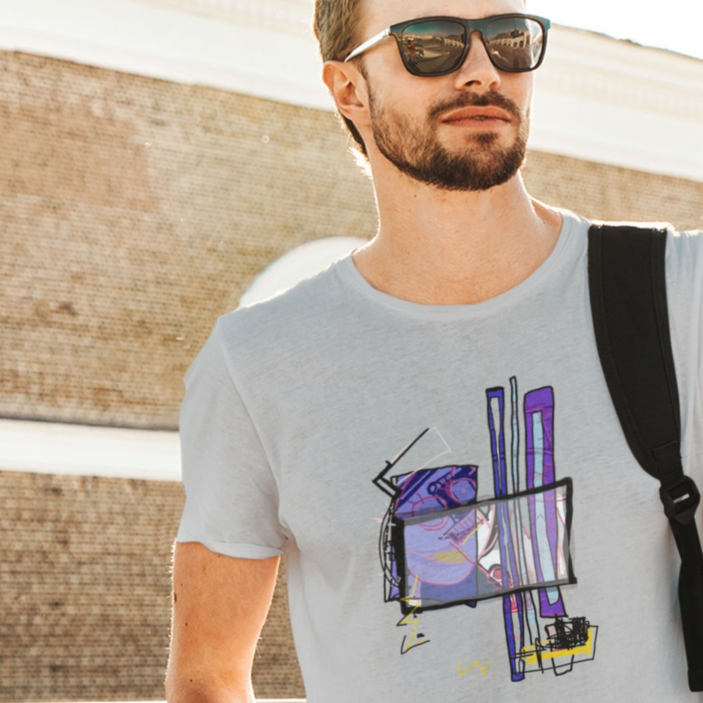 Man wearing a gray t-shirt with a colorful graphic design, standing outdoors.