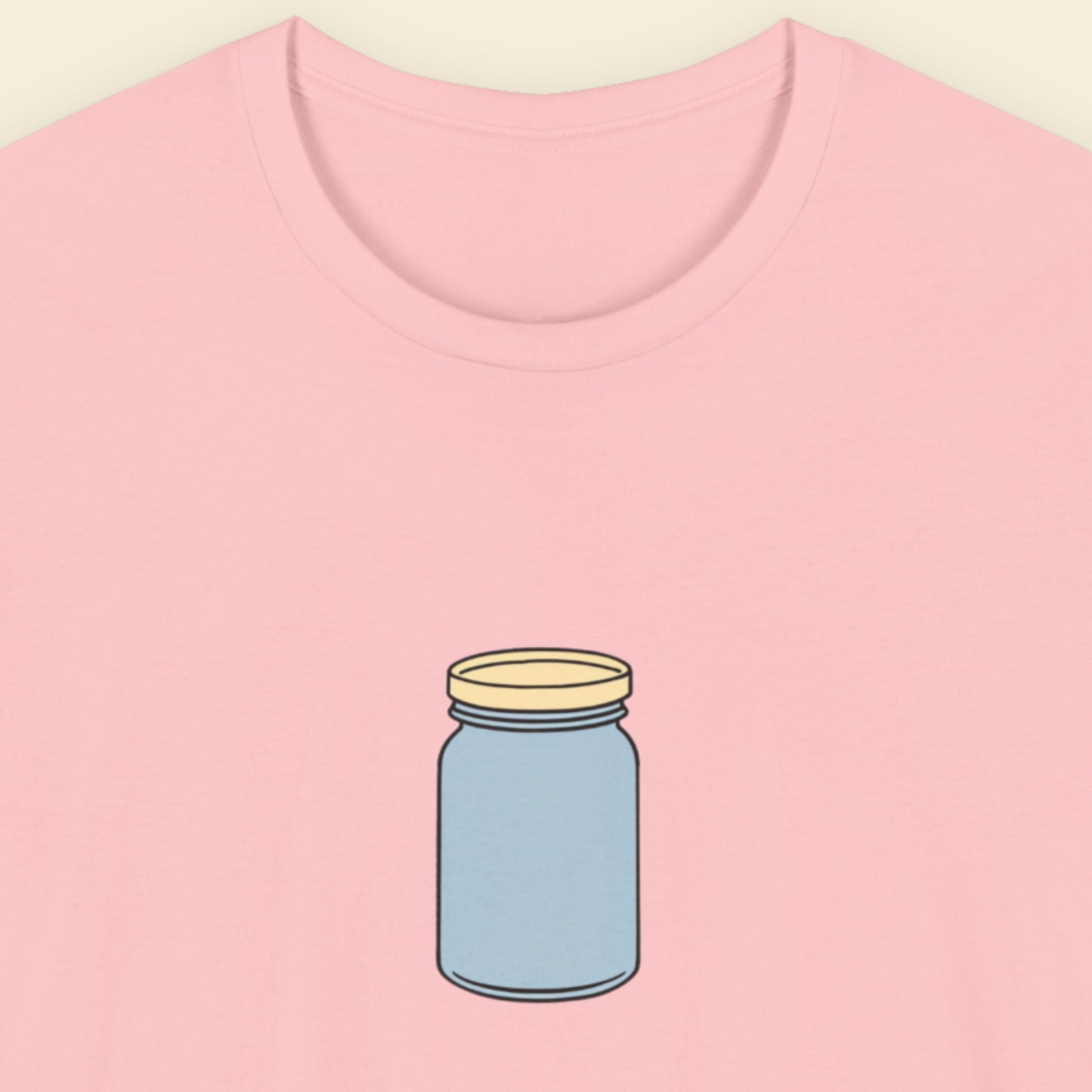 Pink t-shirt with a simple drawing of a blue jar with a beige lid on a beige background.