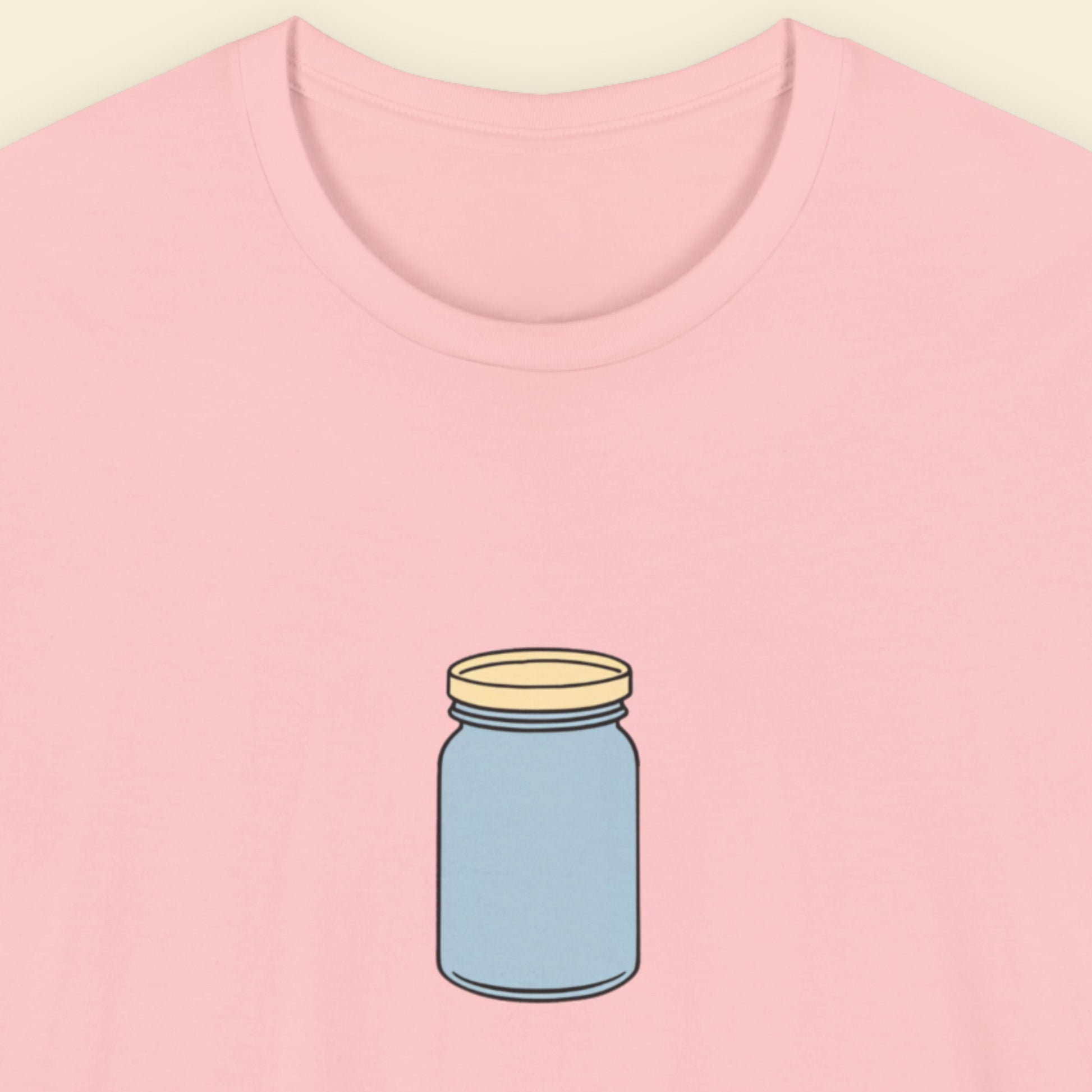 Pink t-shirt with a simple drawing of a blue jar with a beige lid on a beige background.