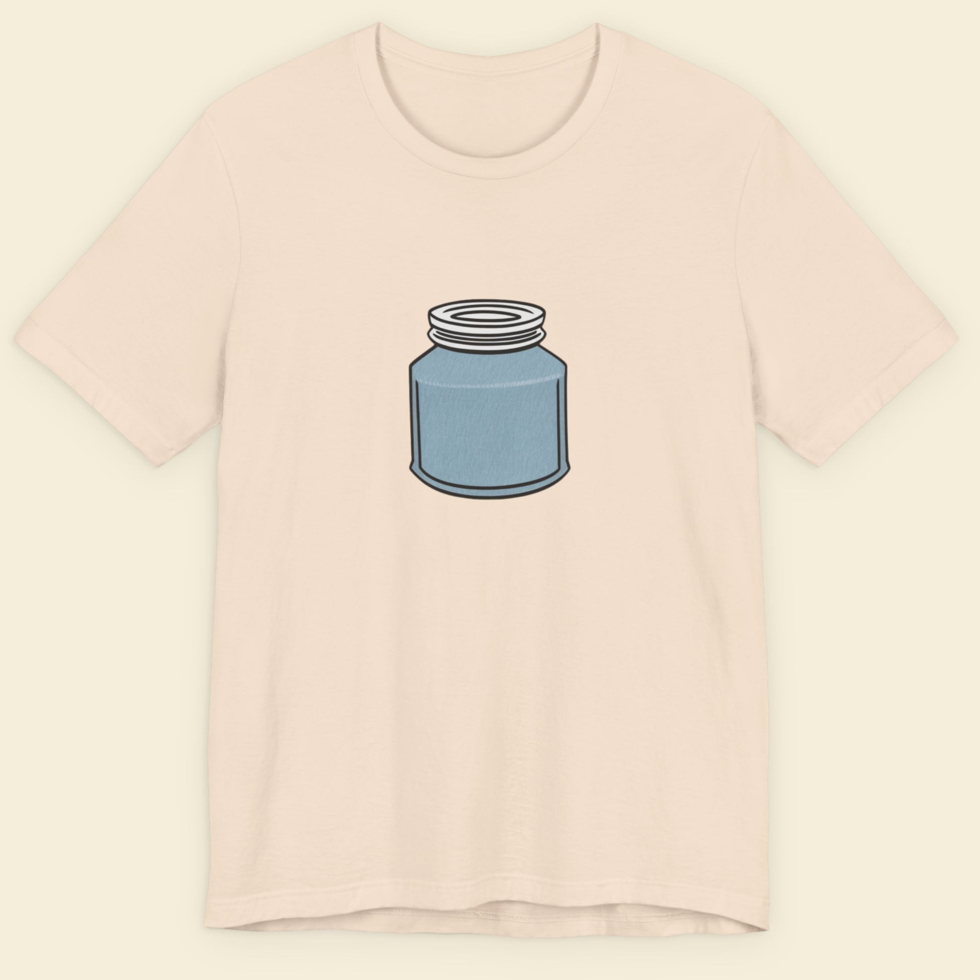Beige shirt with a drawing of a blue jar with a screw top lid on a beige background.