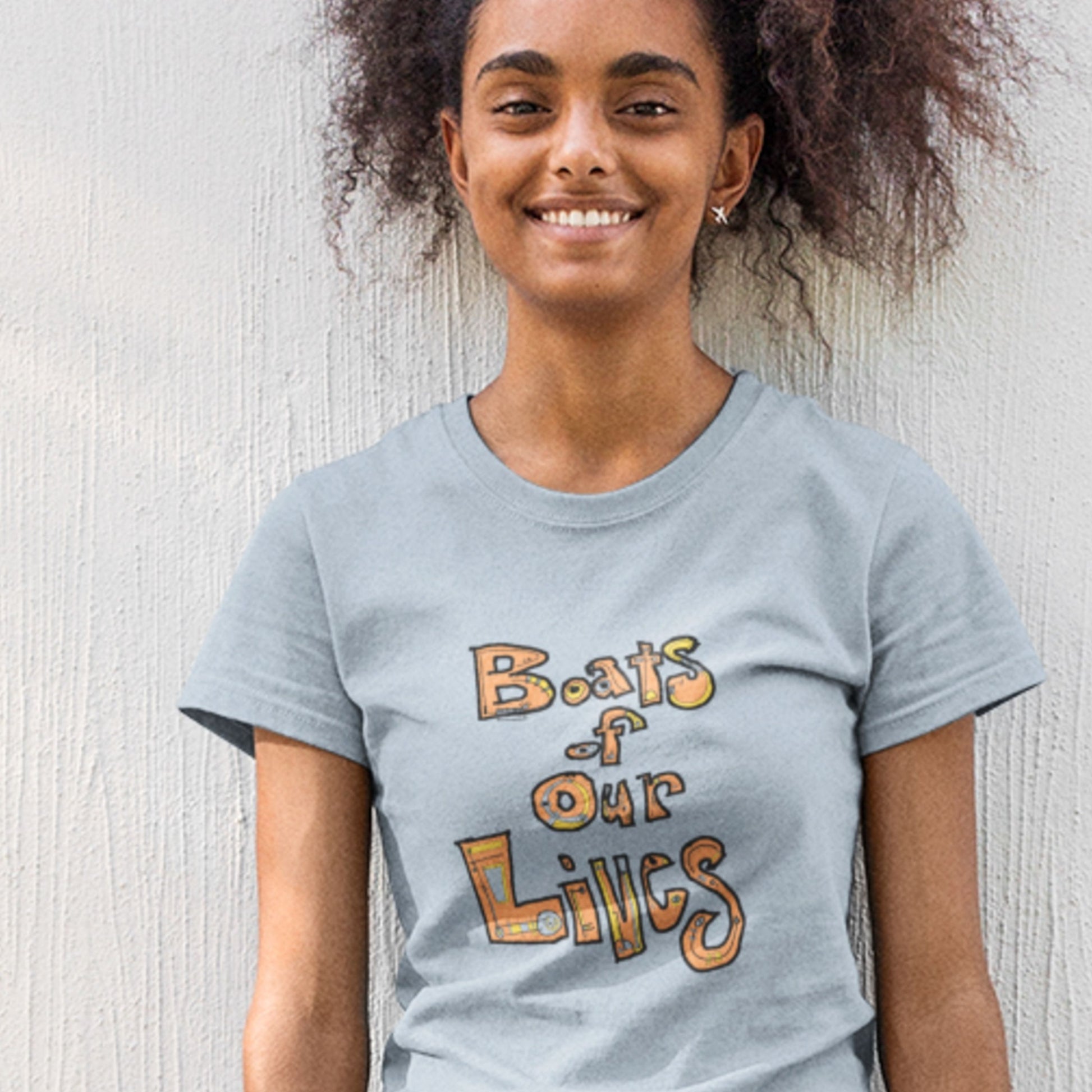 Person wearing a light blue t-shirt with 'Boats of Our Lives' text against a light background