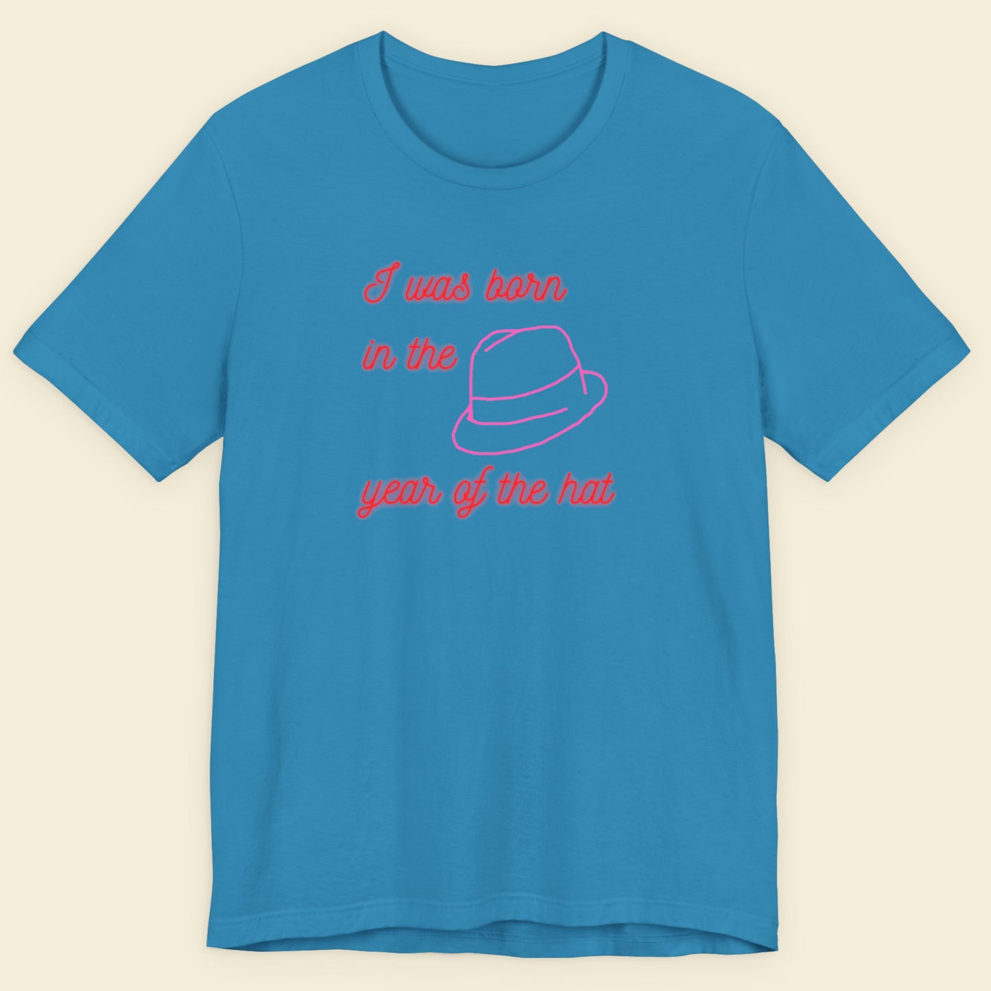 Blue t-shirt with pink text and graphic on a beige background.