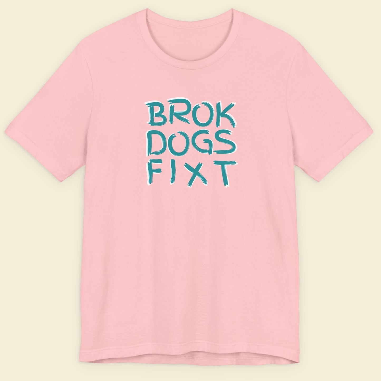 Pink t-shirt with blue text 'BROK DOGS FIXT' on a beige background.