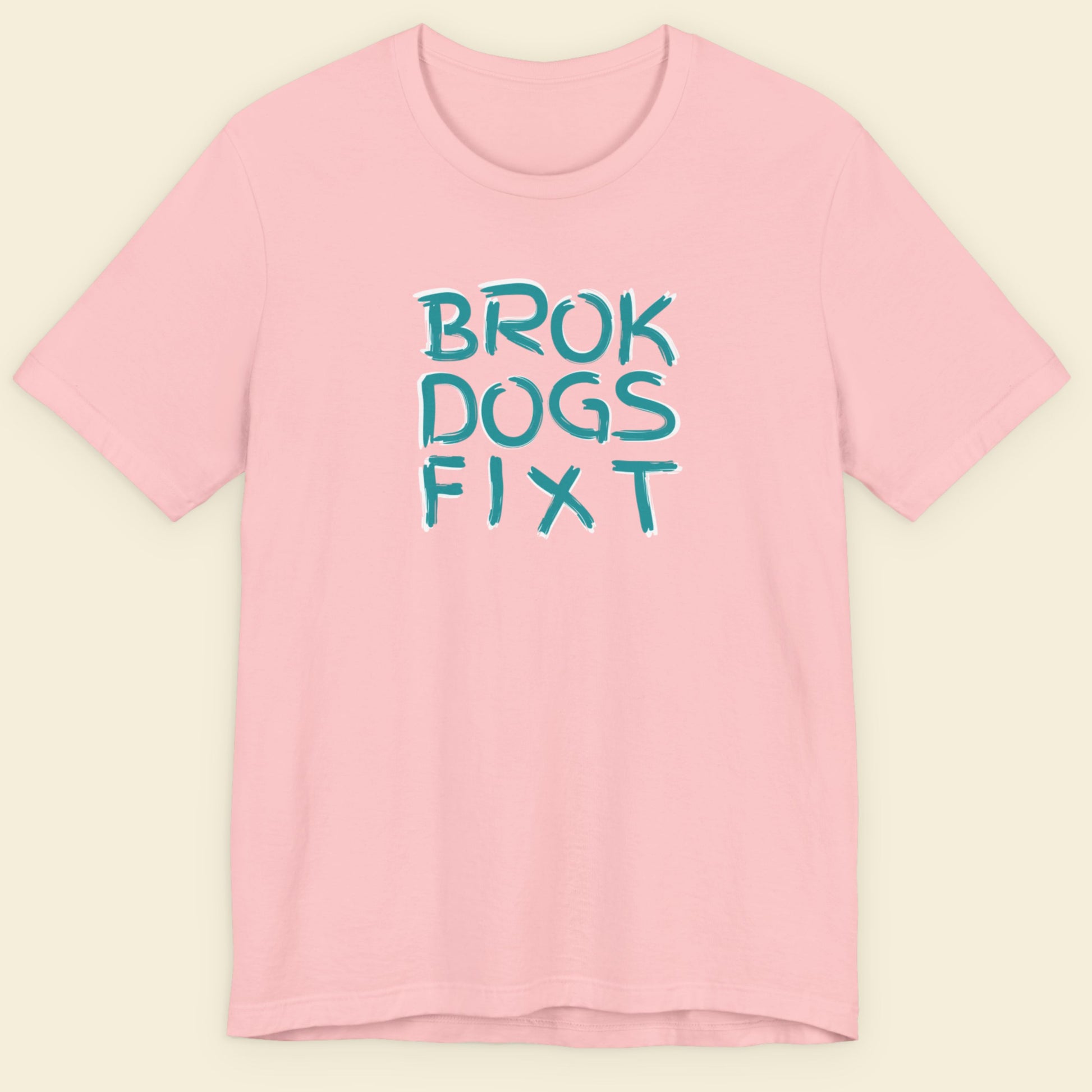 Pink t-shirt with blue text 'BROK DOGS FIXT' on a beige background.