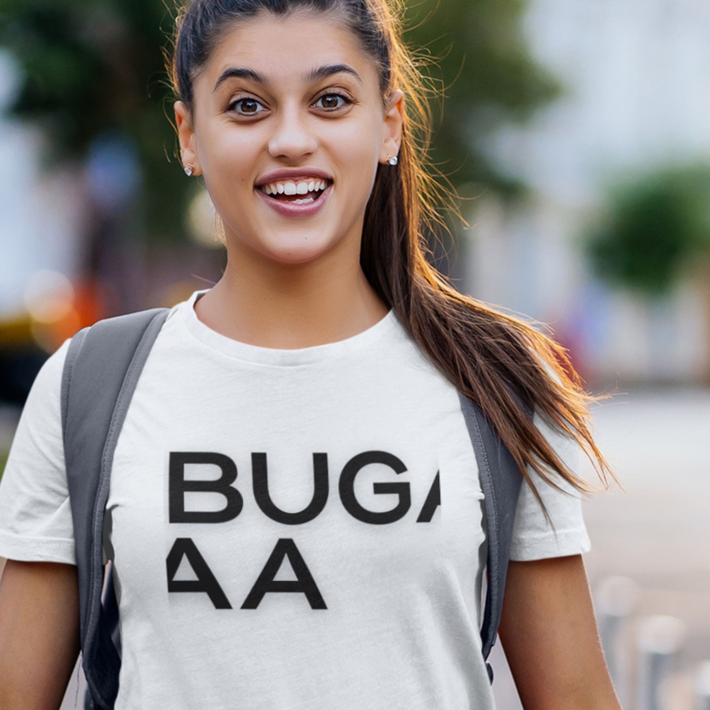 Woman wearing a white t-shirt with 'BUGA' text, smiling outdoors.