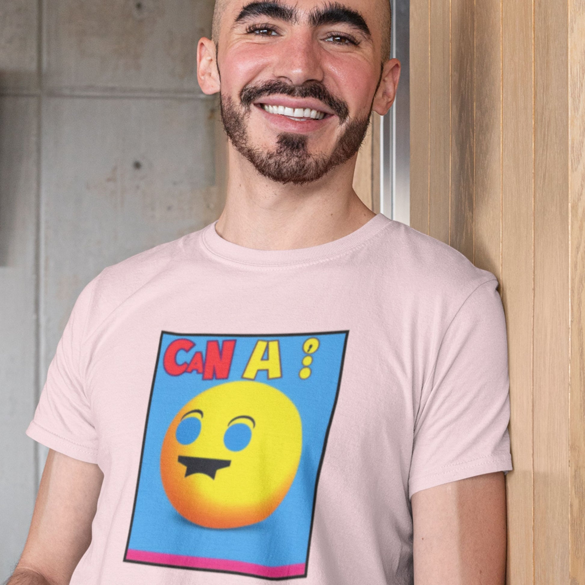 Man wearing a light pink t-shirt with a colorful emoji design and text.