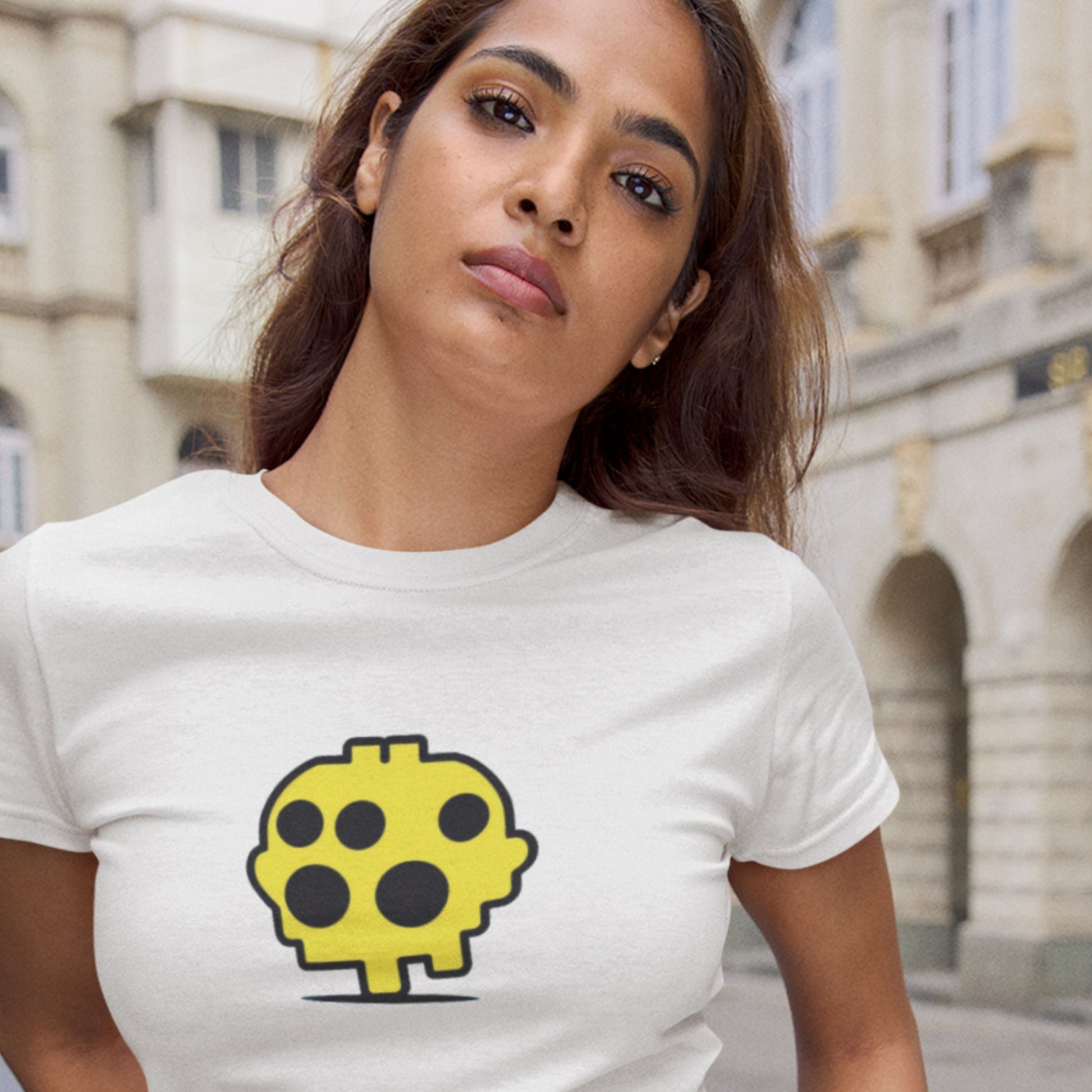 Woman wearing a white t-shirt with a yellow and black graphic design outdoors.