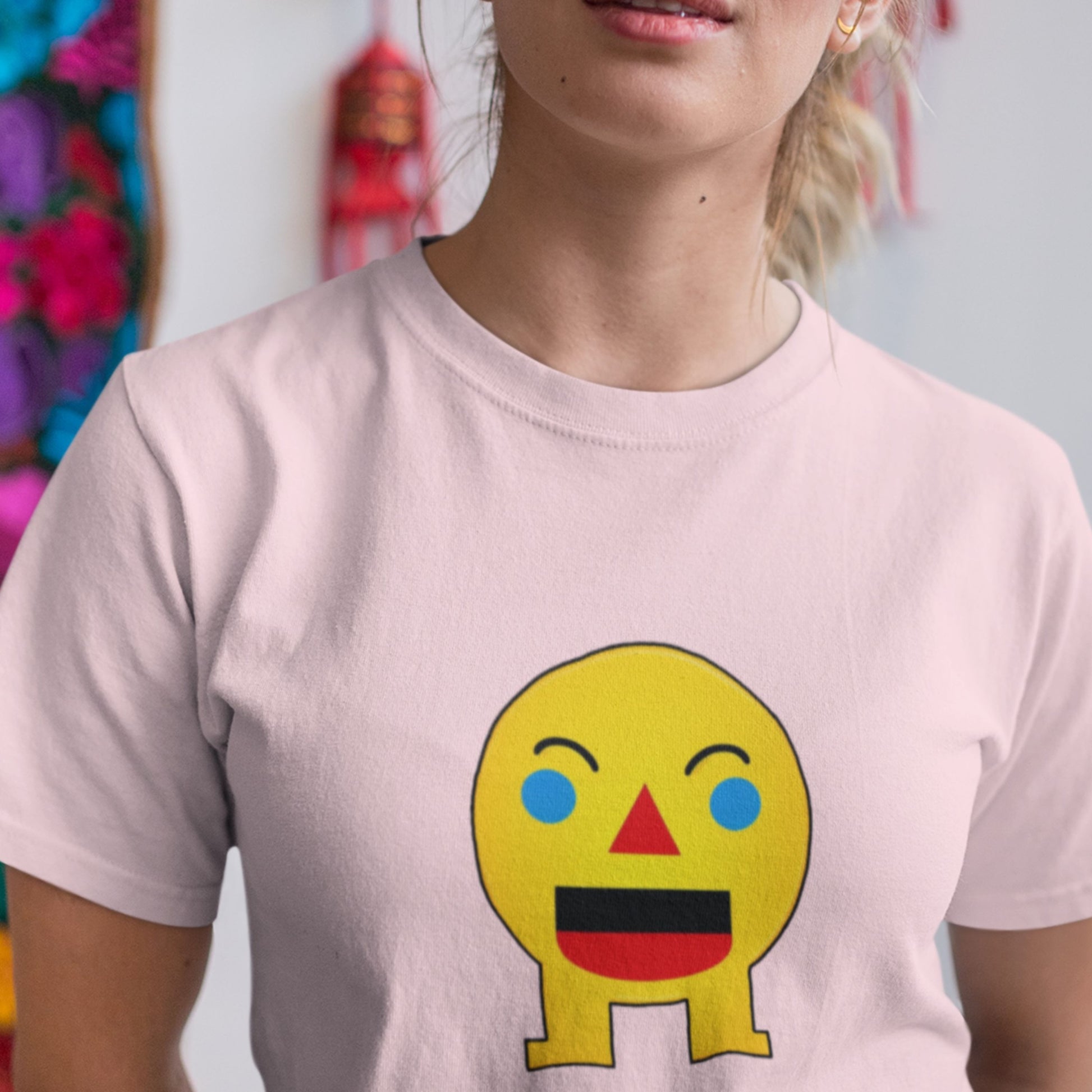 Woman wearing a pink t-shirt with a fun, colorful cartoon illustration in an art room.