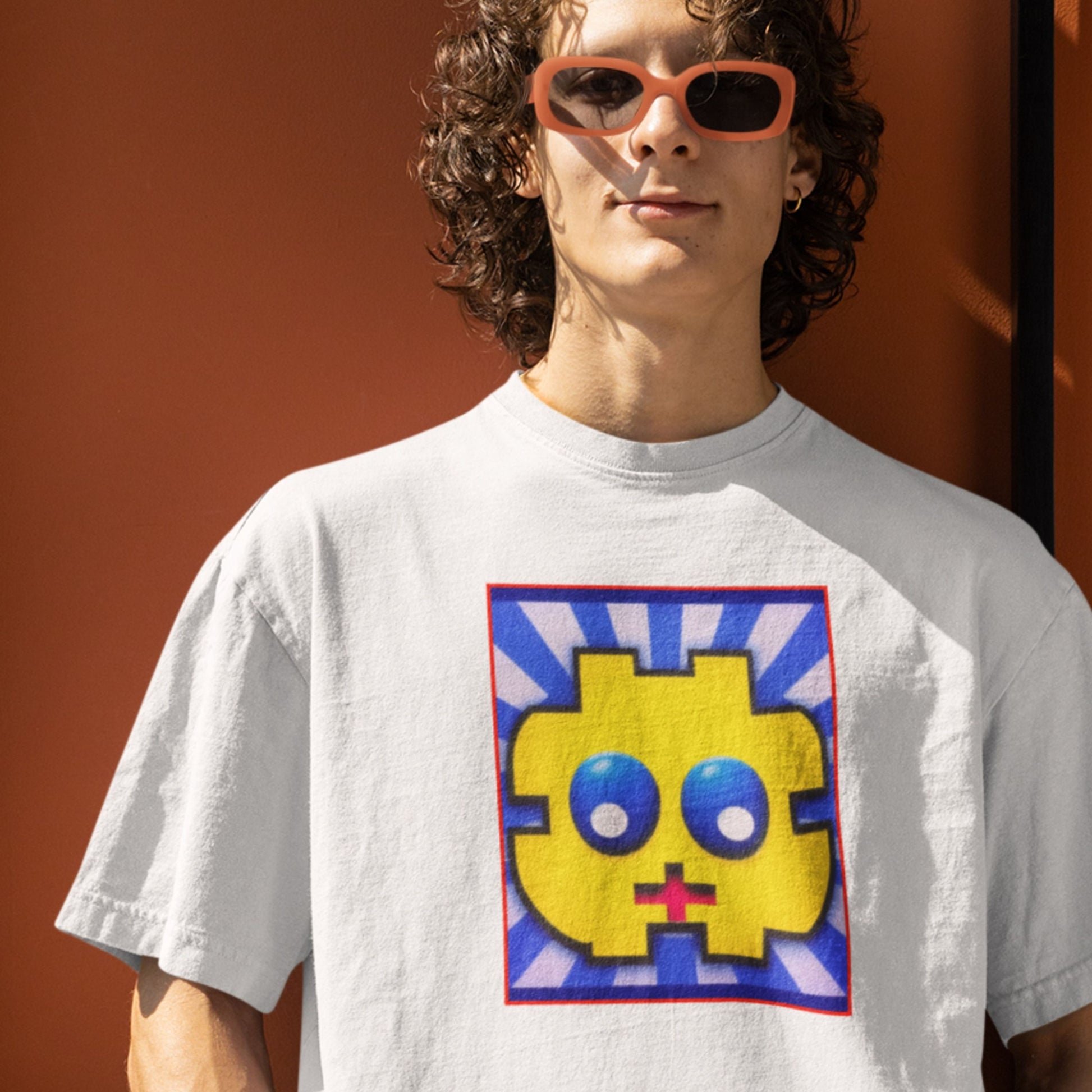 Person wearing a white t-shirt with a colorful graphic design against an orange background.