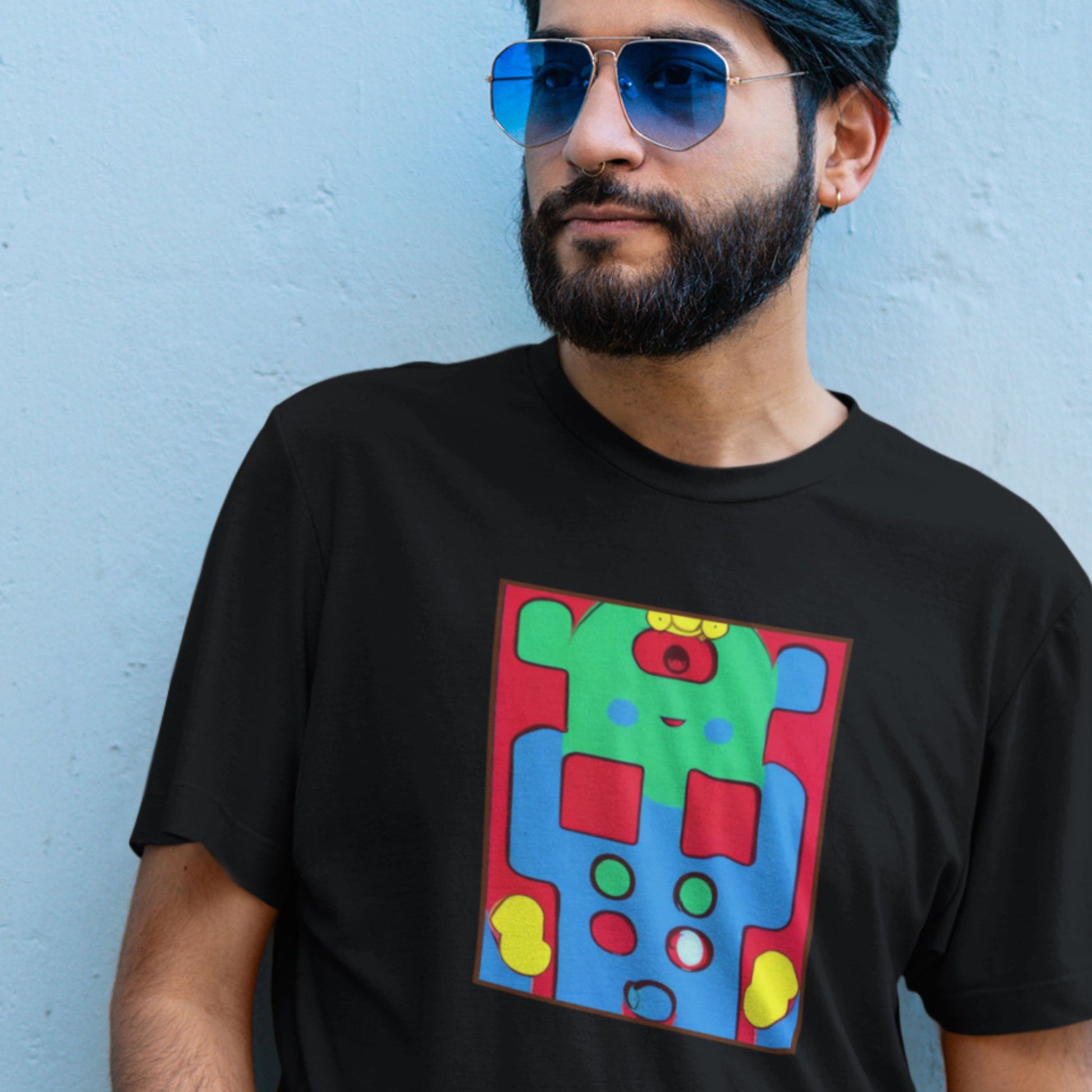 Man wearing a black t-shirt with a colorful graphic design against a light blue wall.