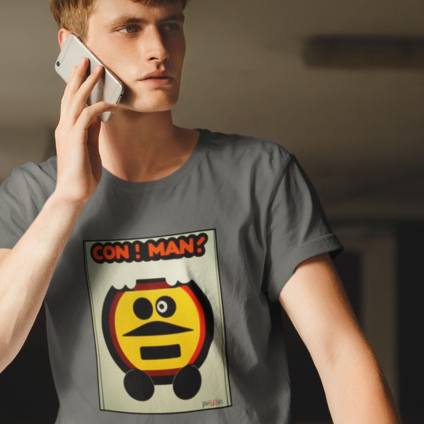 Person wearing a t-shirt with a graphic design and text, holding a phone to their ear.