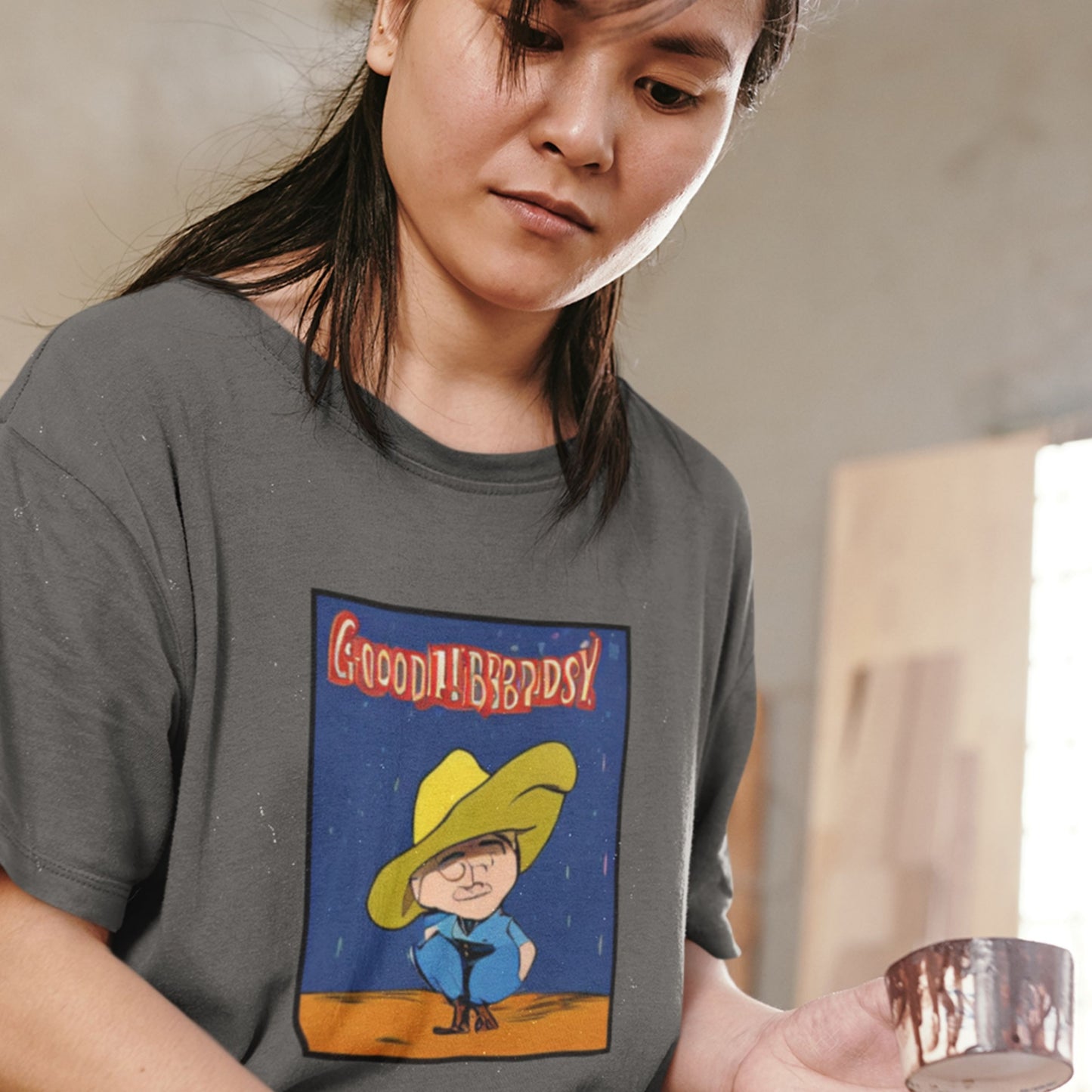 Person wearing a t-shirt with a graphic design of a character in a yellow hat.