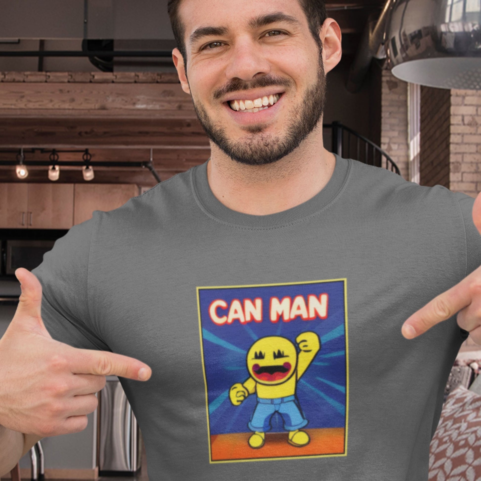 Smiling man wearing a grey t-shirt with a fun, colorful cartoon illustration in a restaurant.