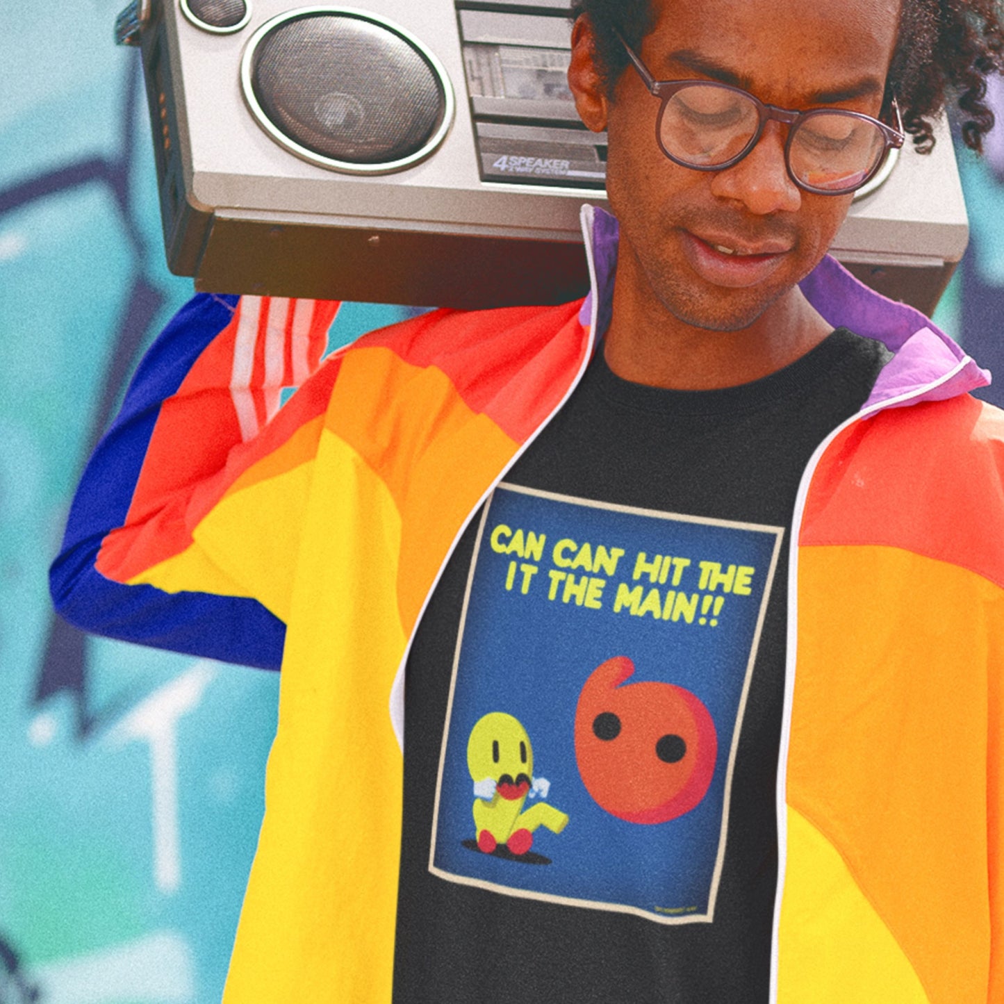 Person wearing a colorful jacket and graphic t-shirt with a retro-themed design, standing against a graffiti-covered wall.