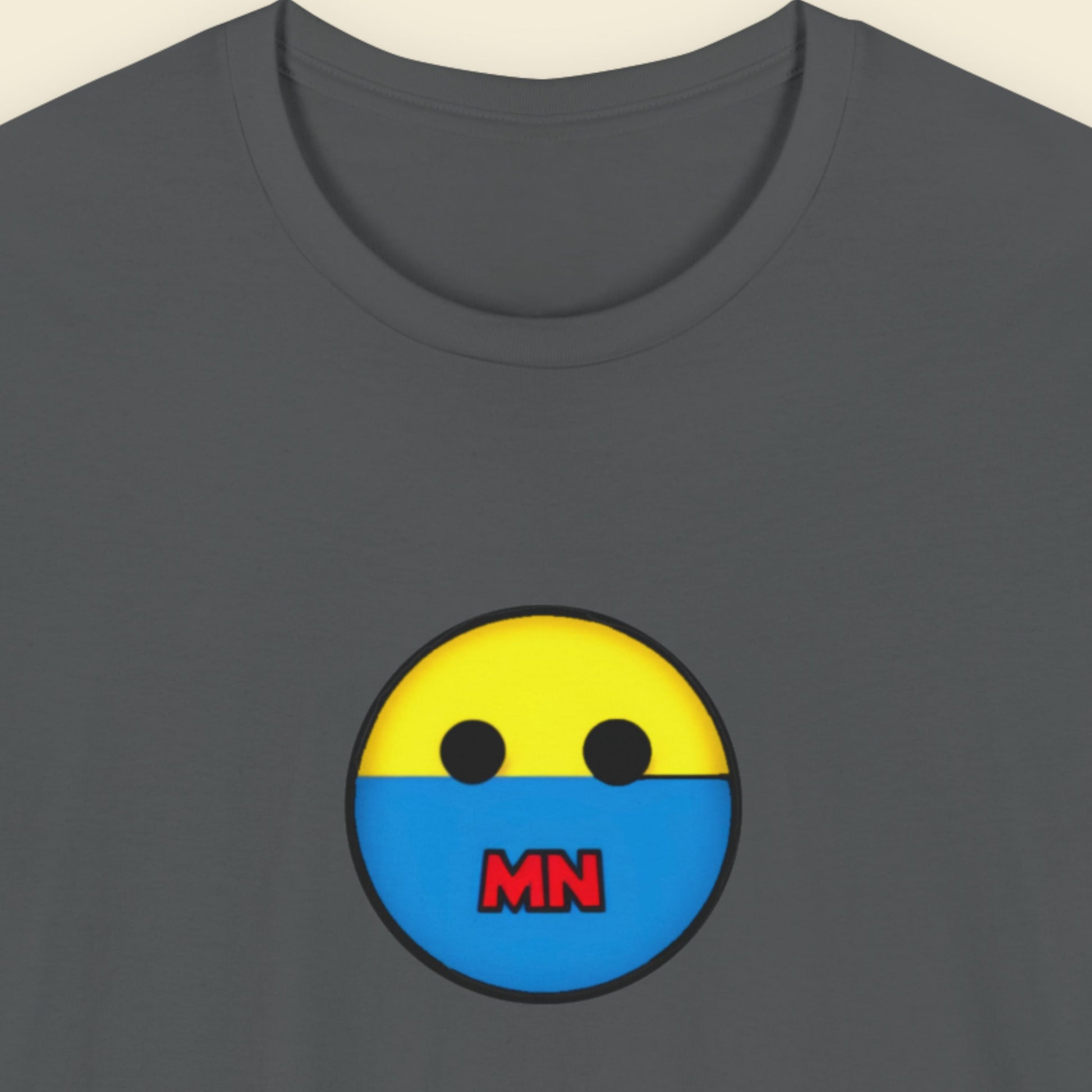 Gray t-shirt with a yellow and blue face design featuring 'MN' on a beige background.