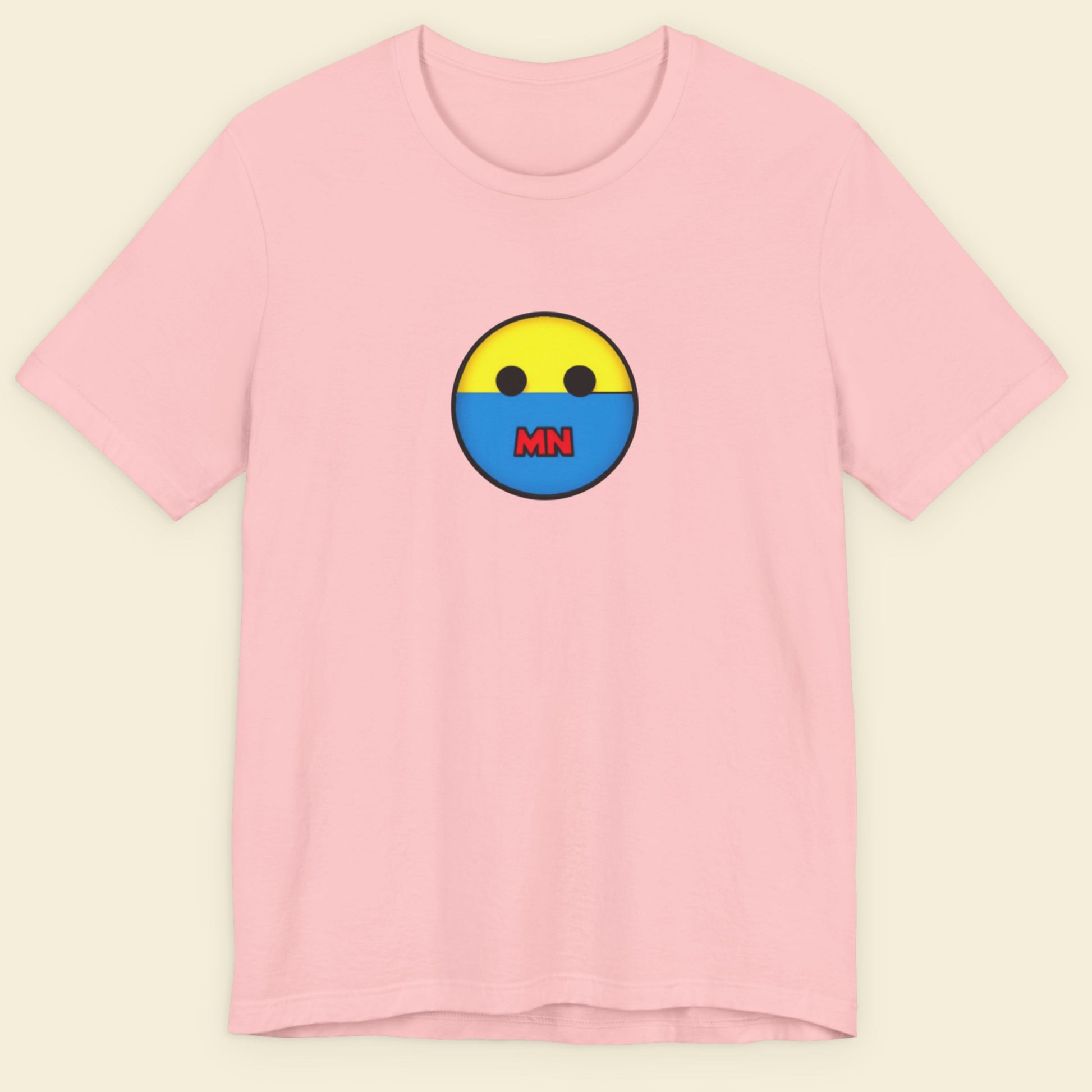 Pink t-shirt with a colorful smiley face design on a beige background.