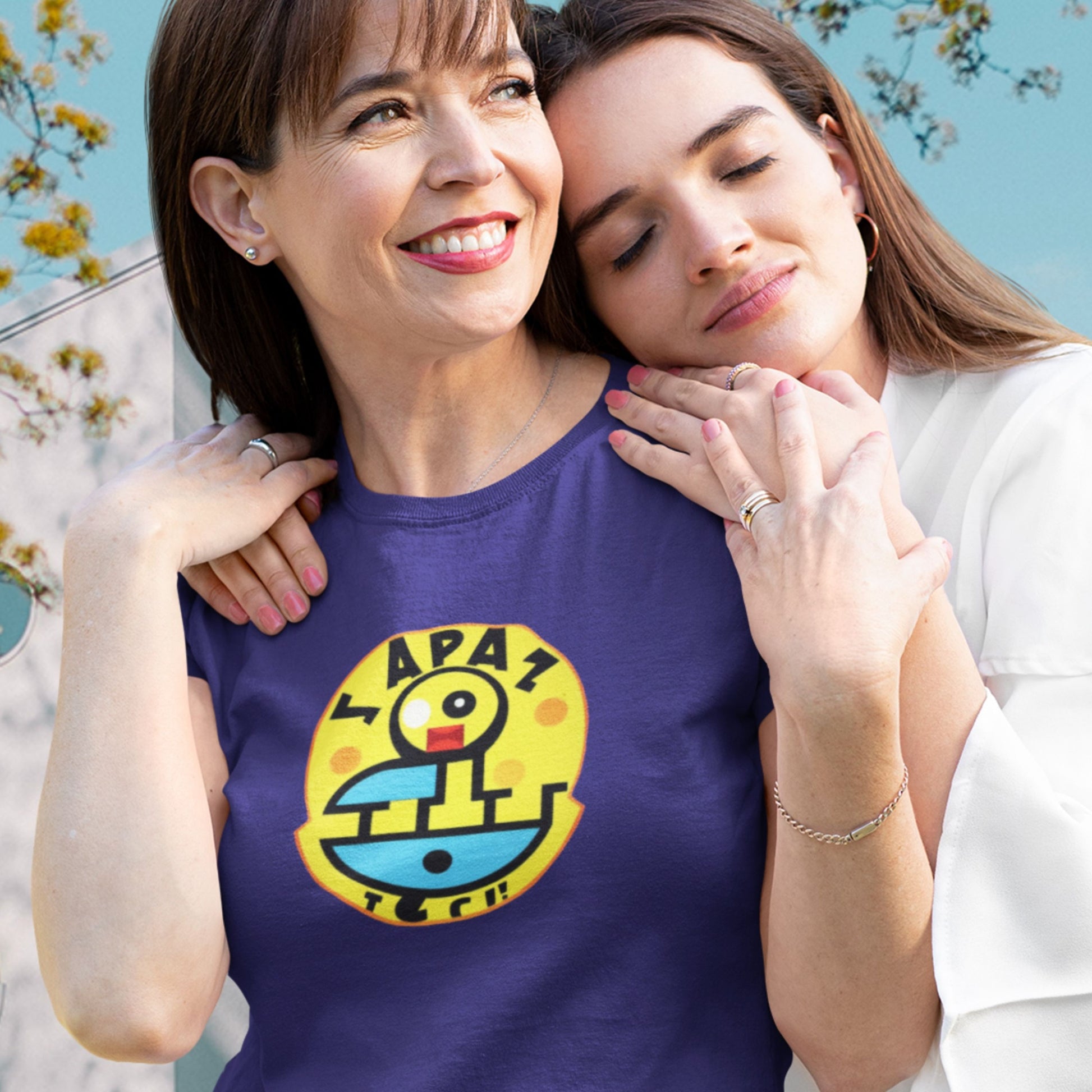 Woman wearing a navy blue t-shirt with a fun, colorful nonsense cartoon illustration outside with her daughter.