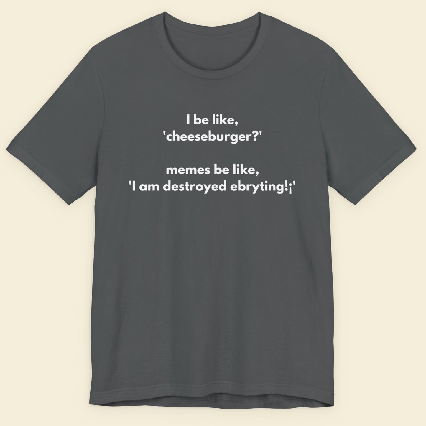 Gray t-shirt with humorous text design on a beige background.